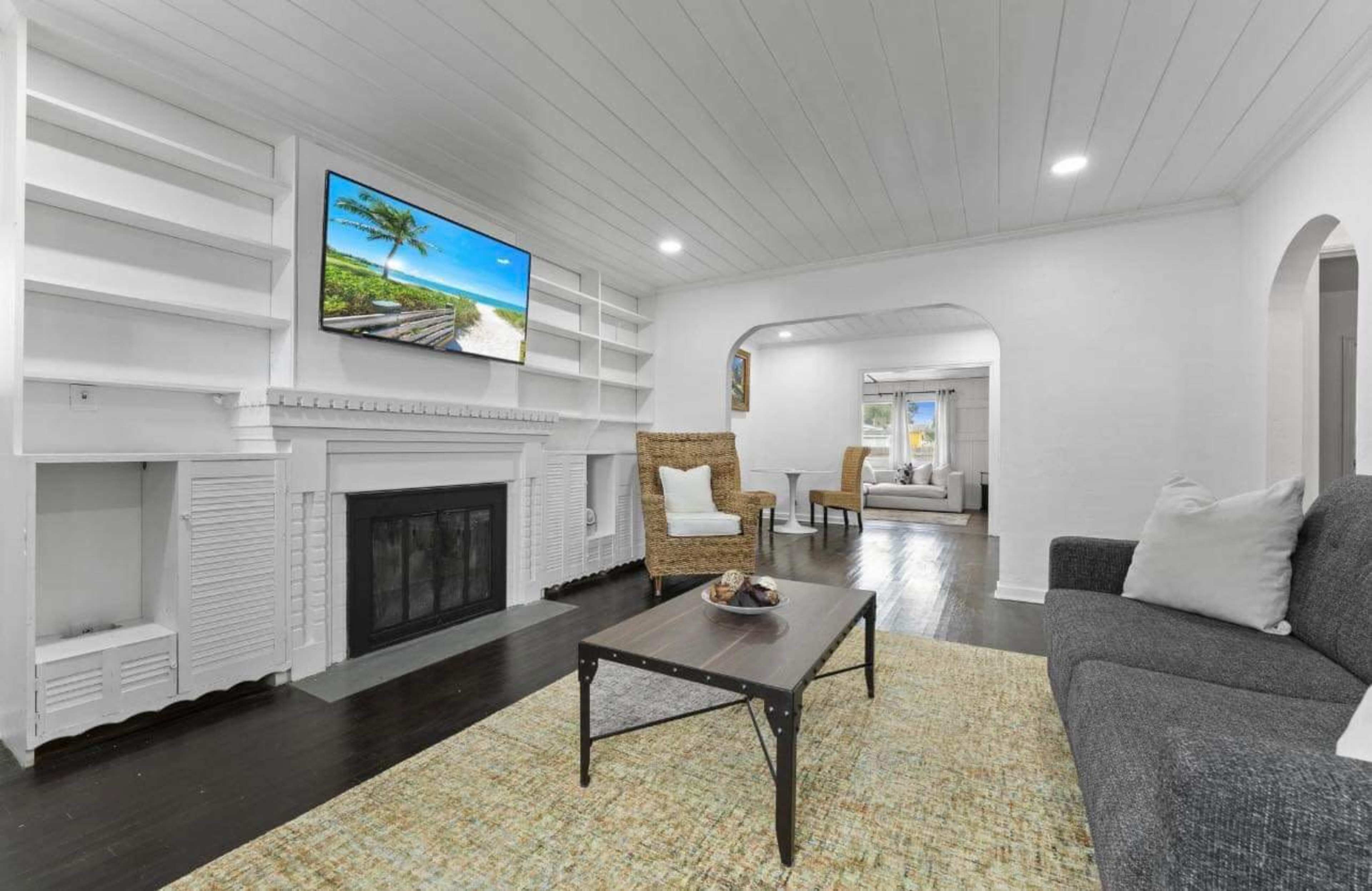A living room with a sofa, a coffee table, a fireplace, and a large TV mounted on the wall, surrounded by built-in shelves.