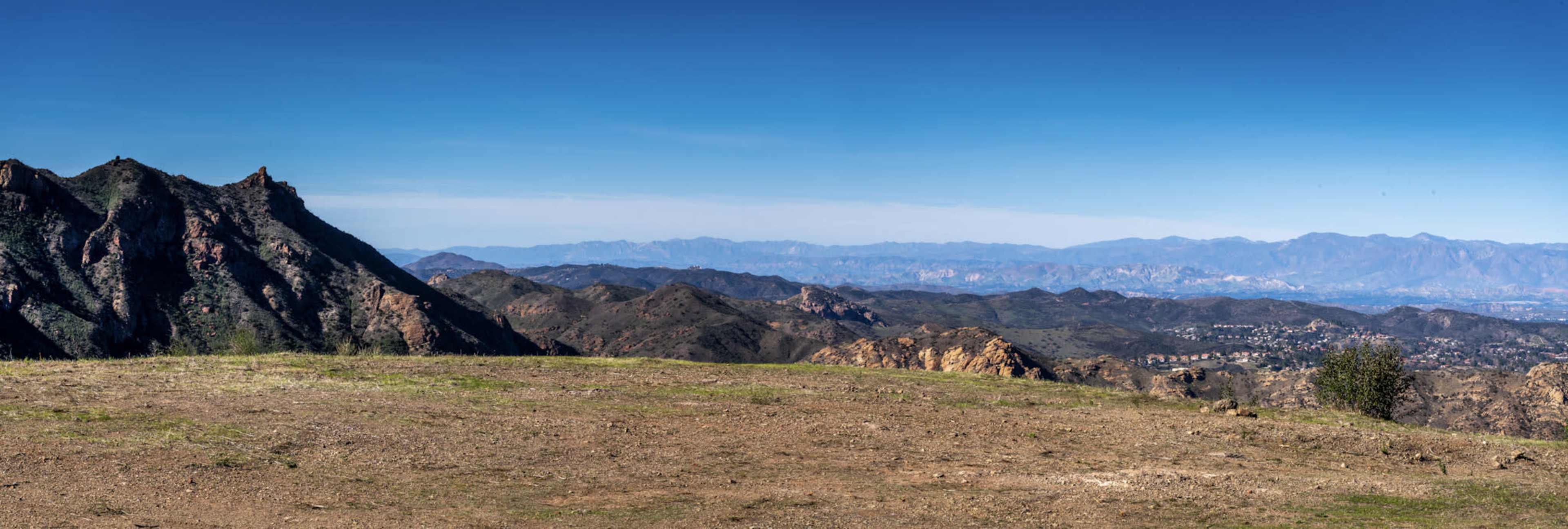 The image shows a panoramic view of mountainous terrain under a clear blue sky.