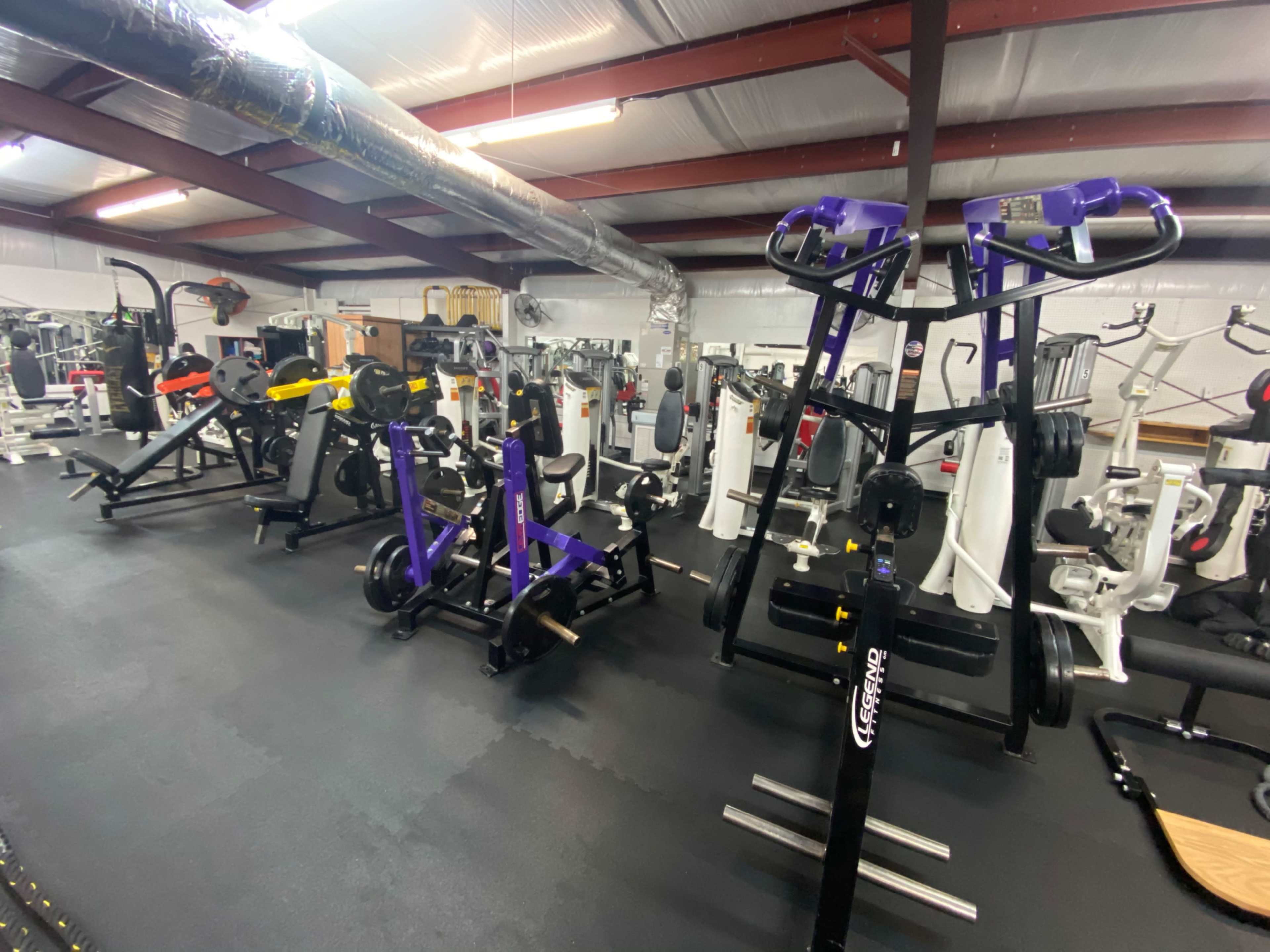 A gym interior with various exercise equipment, including stationary bikes and weight machines, organized in a spacious layout.