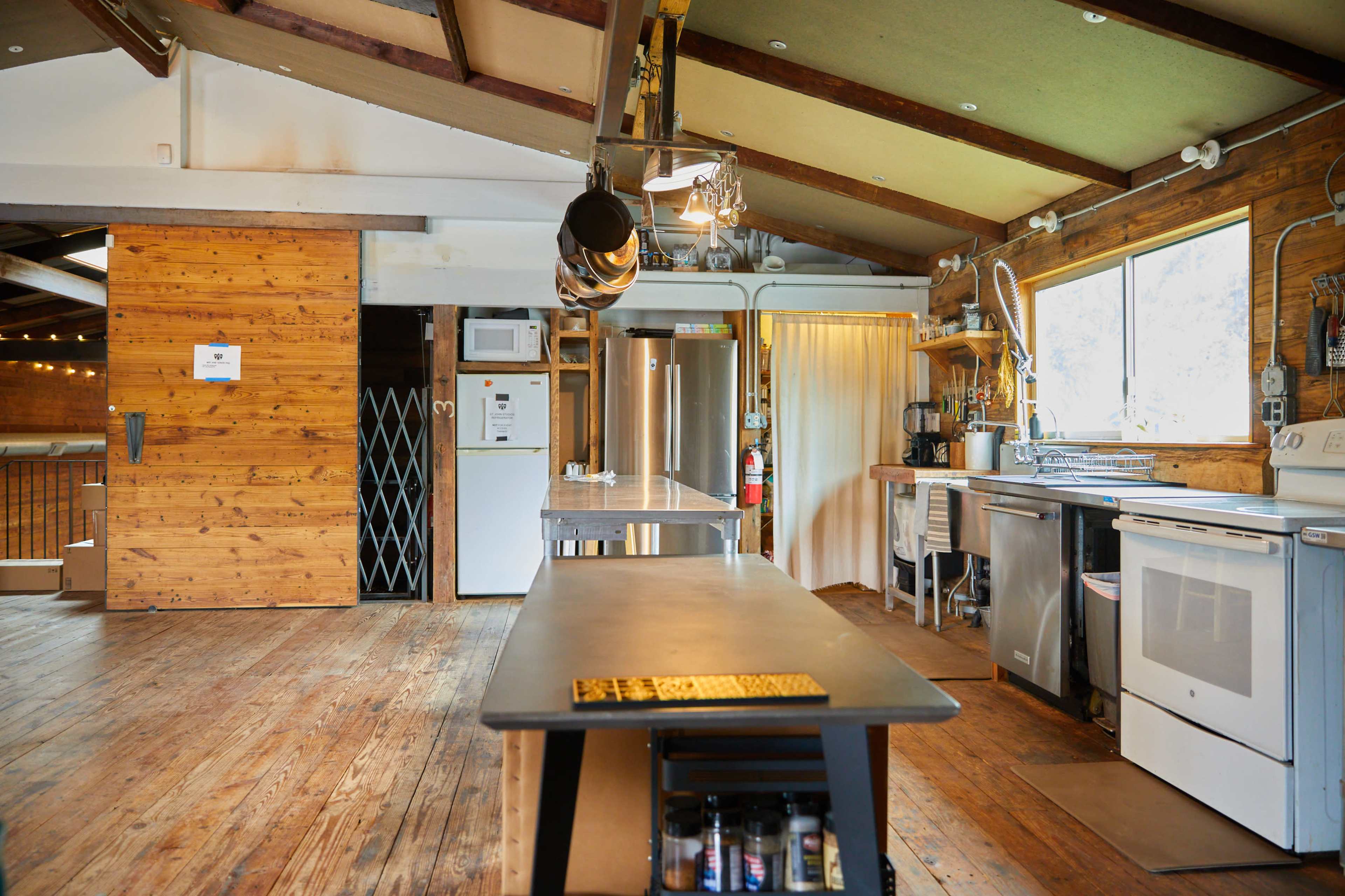 A spacious kitchen with wooden walls, a central island, and stainless steel appliances.