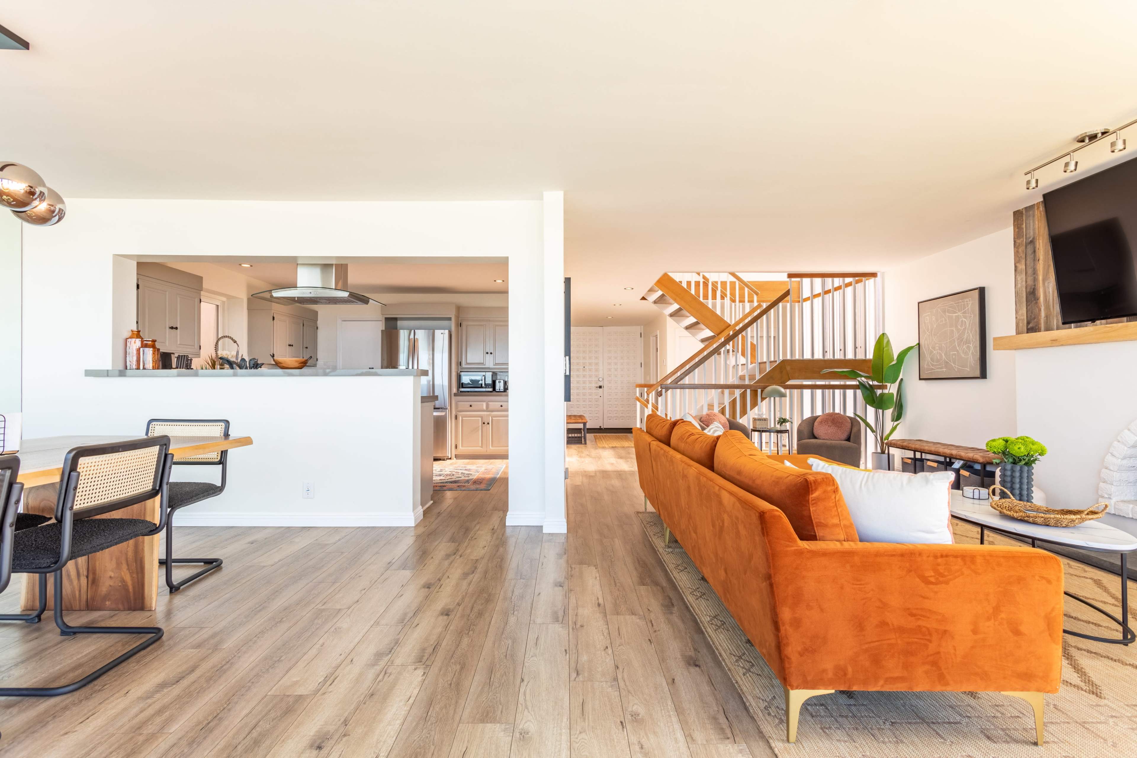 A modern, open-concept living space with a kitchen, dining area, and a staircase leading to an upper level.