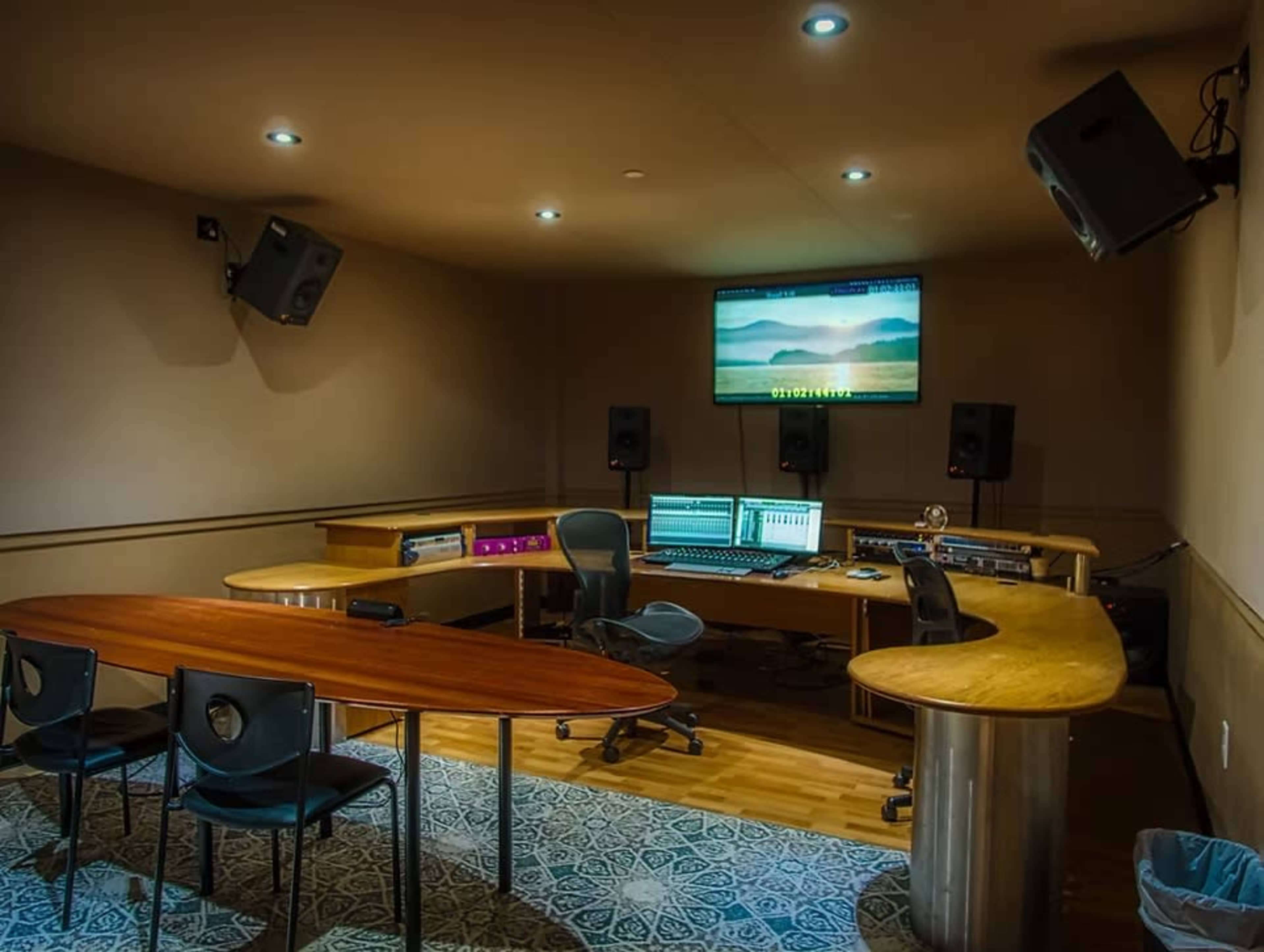 The image shows a sound studio featuring multiple computer monitors, audio equipment, and seating arrangements for collaboration.