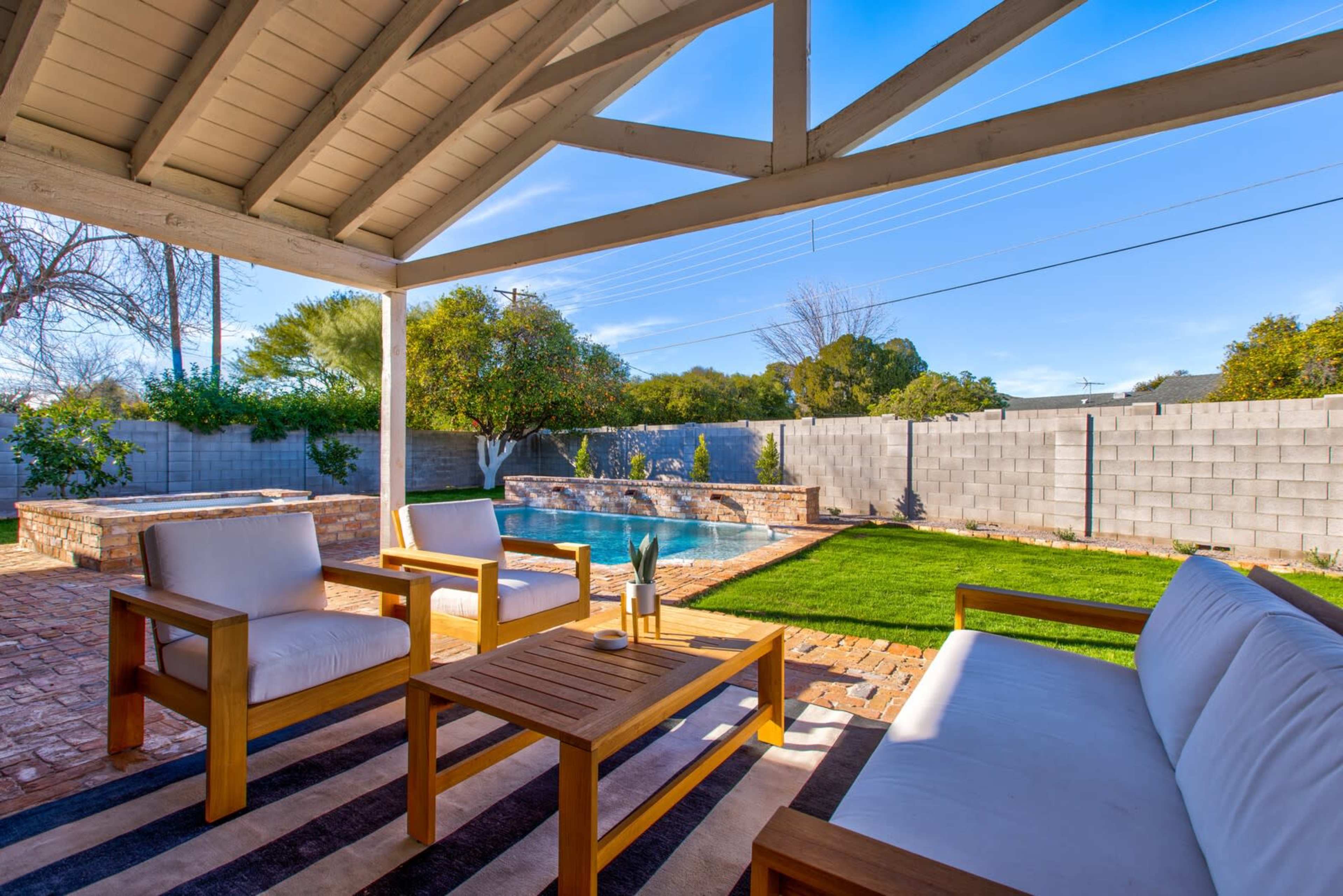 A patio area with wooden furniture and a swimming pool in a well-maintained backyard.