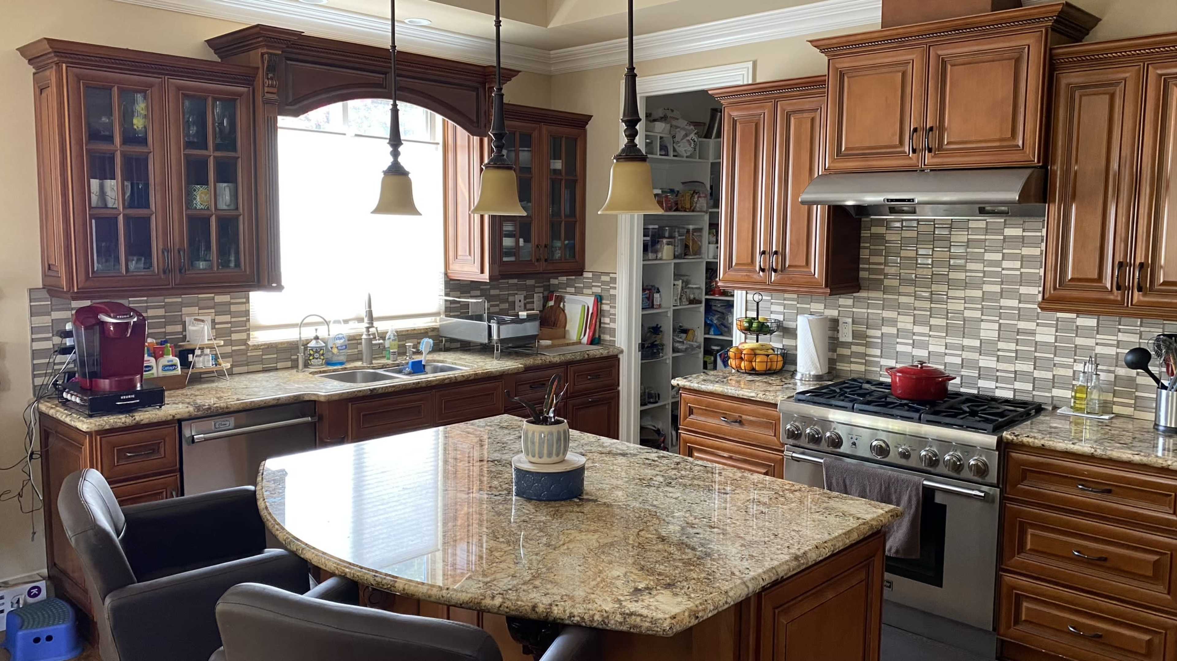 A well-appointed kitchen with wooden cabinets, a central island, and a variety of appliances, including a stovetop and a coffee maker.