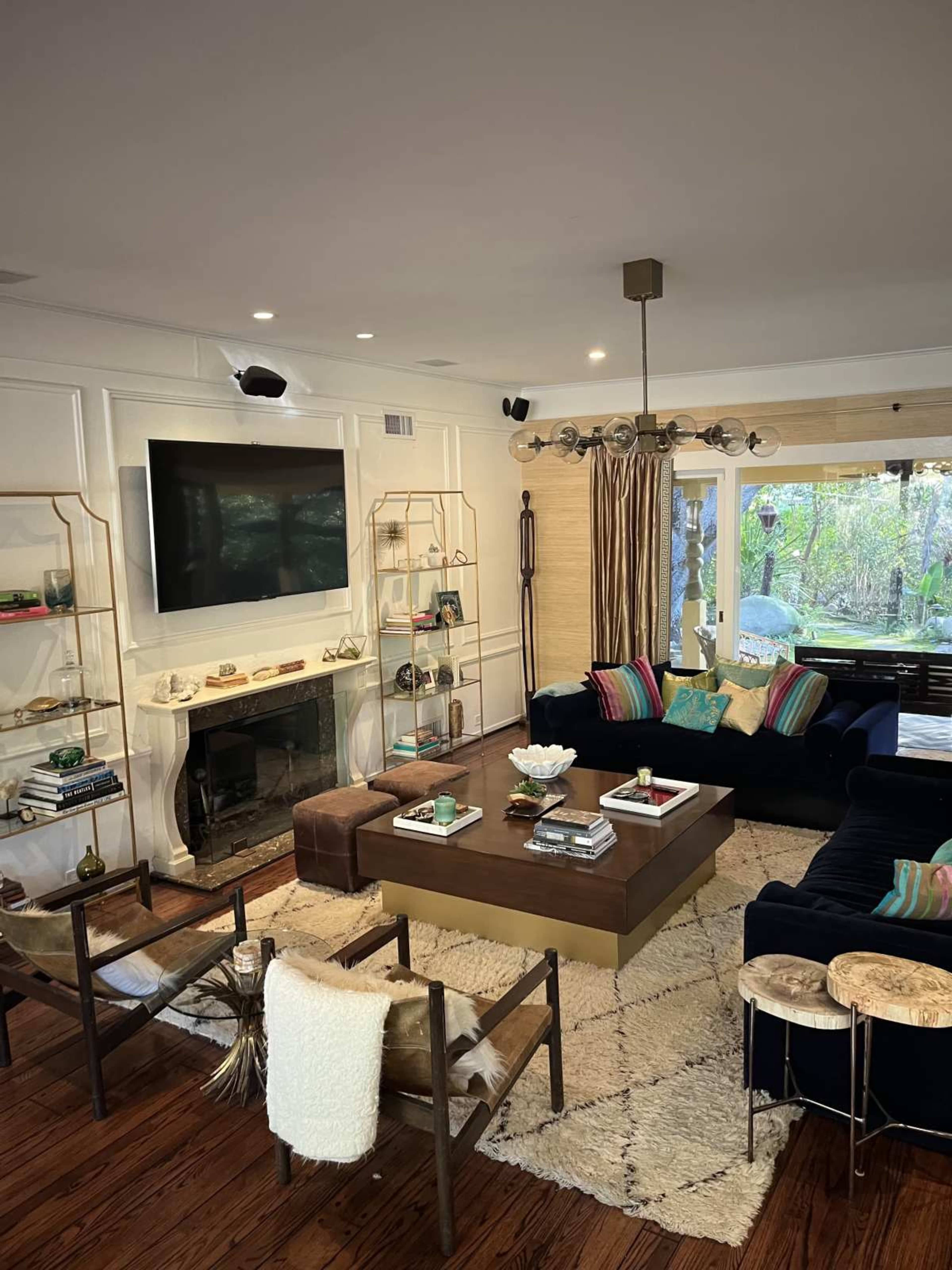 The living room features a dark blue sectional sofa, a wooden coffee table, a mounted television, and bookshelves displaying decorative items and books.