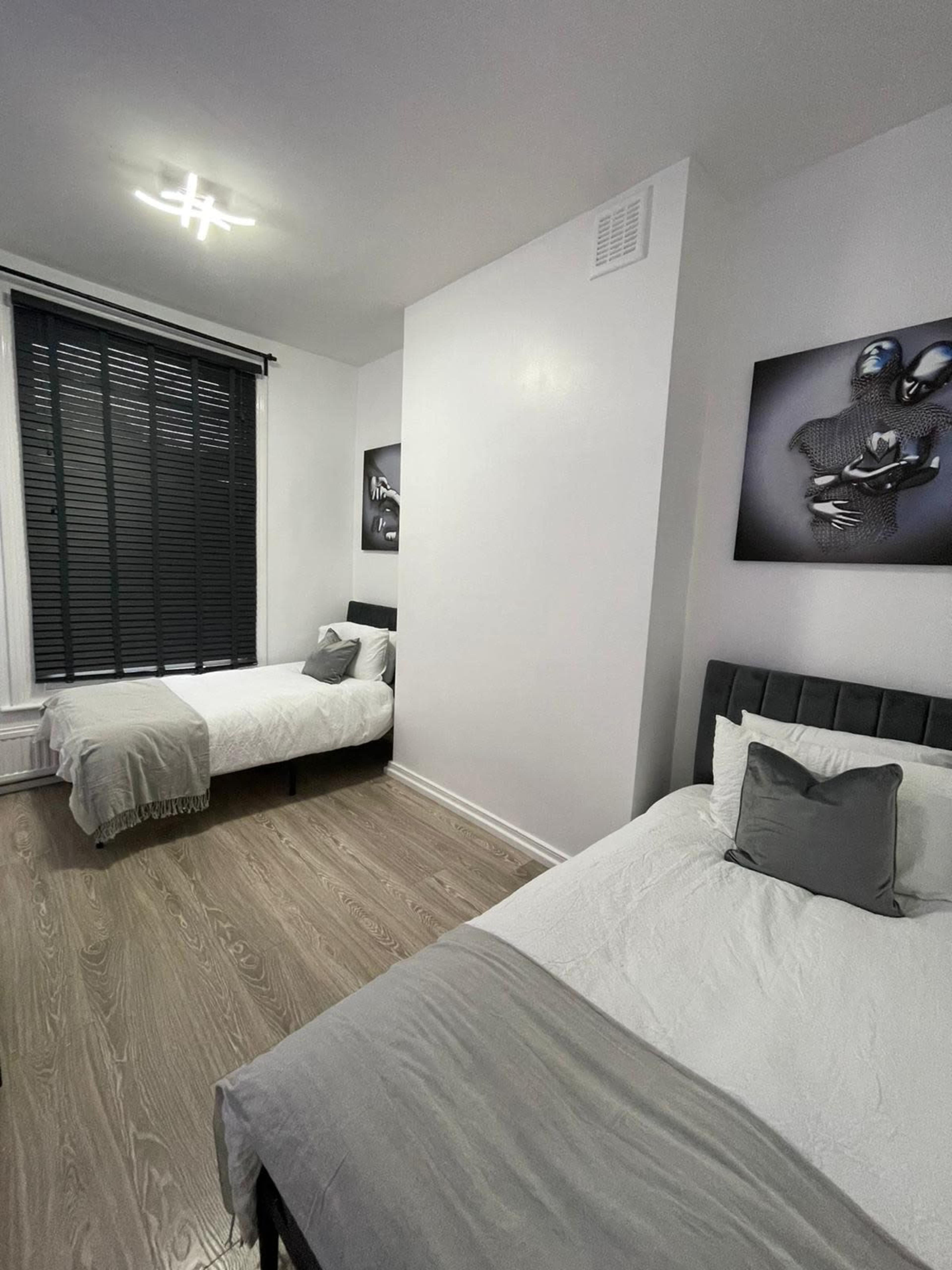 A modern bedroom featuring two single beds with gray accents and framed artwork on the walls.