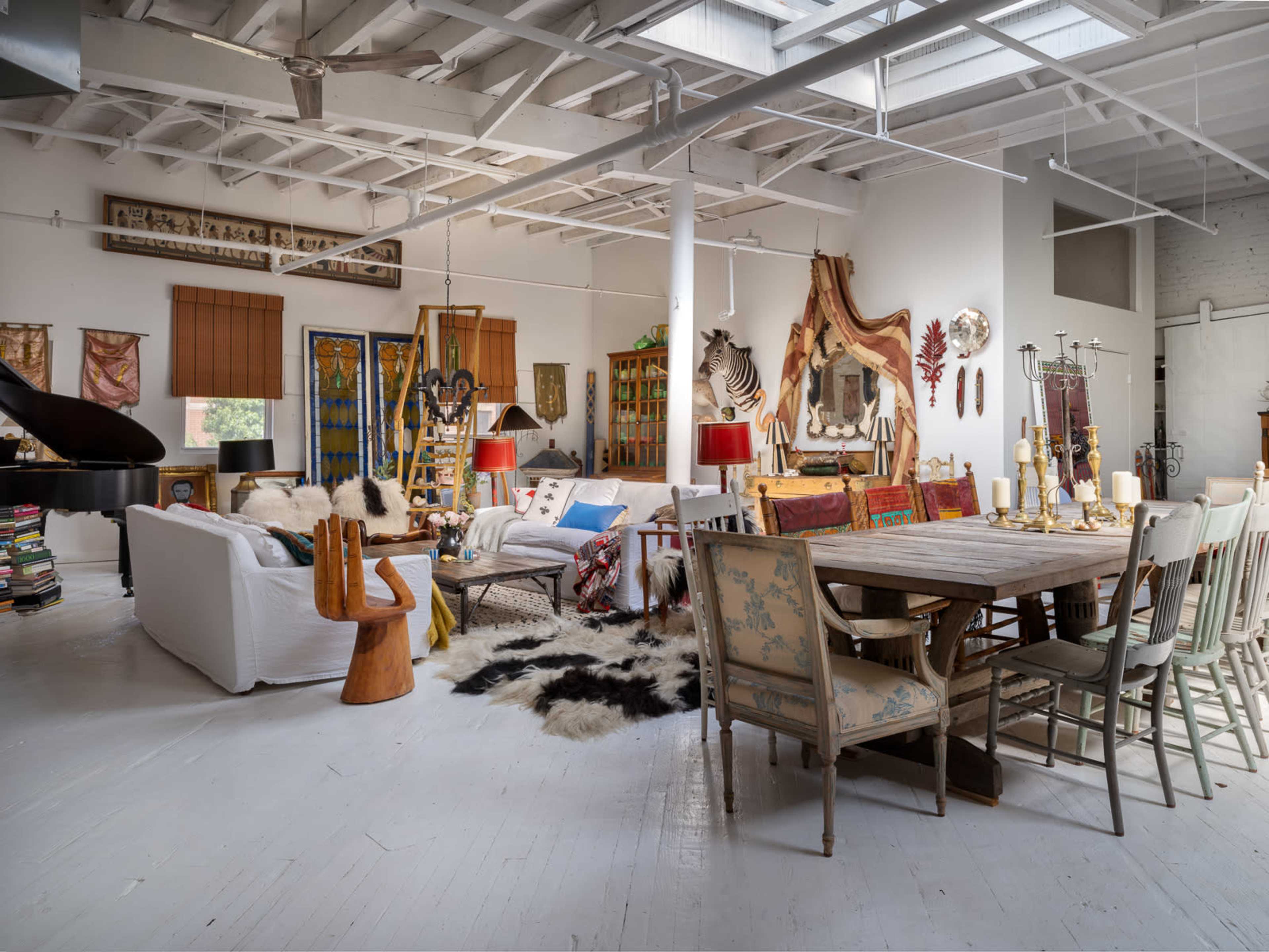 A spacious and eclectic interior with a mix of furniture styles, artwork, and decorative elements in a well-lit room.