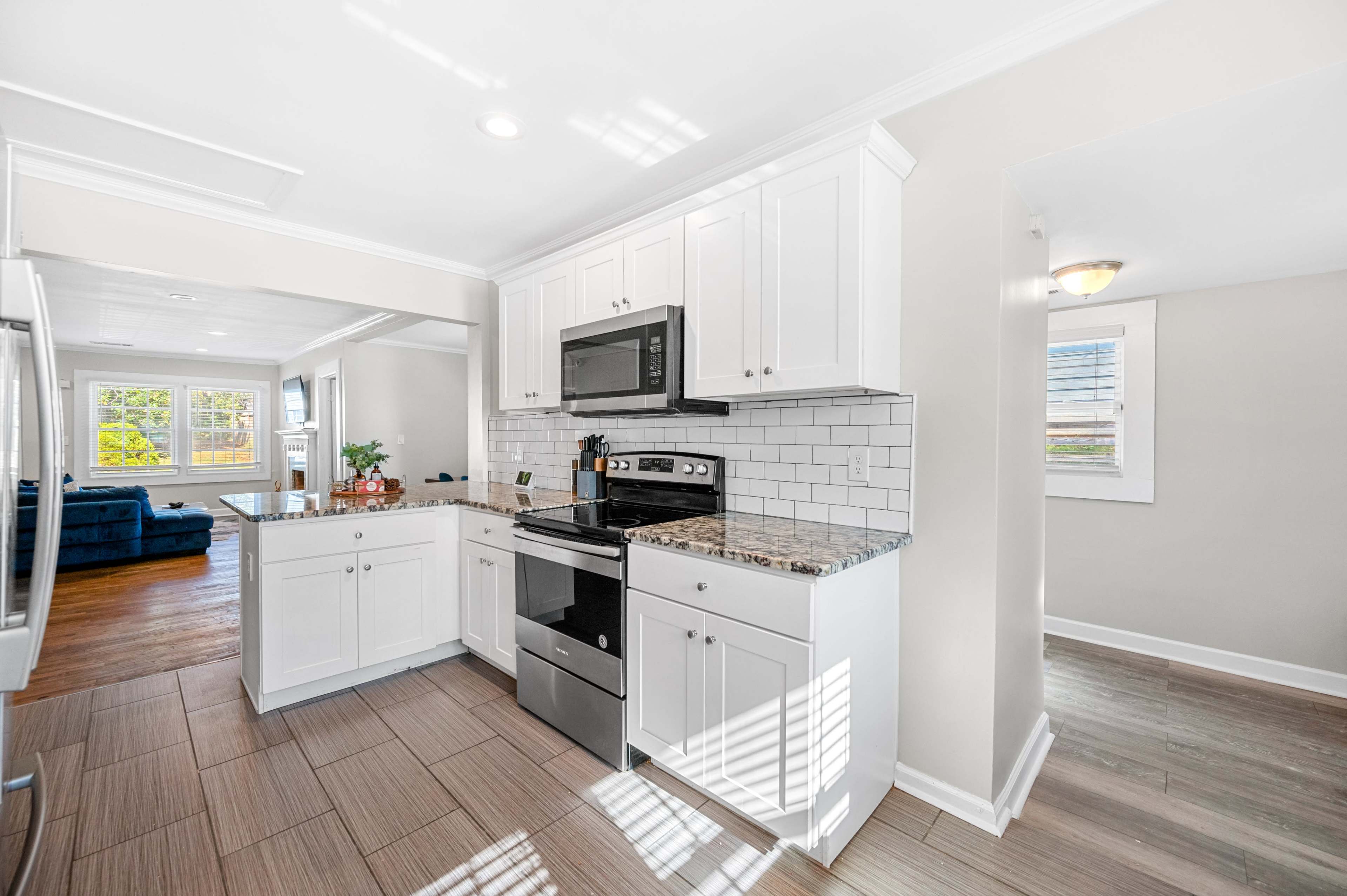 A modern kitchen features white cabinetry, stainless steel appliances, and a tiled backsplash.