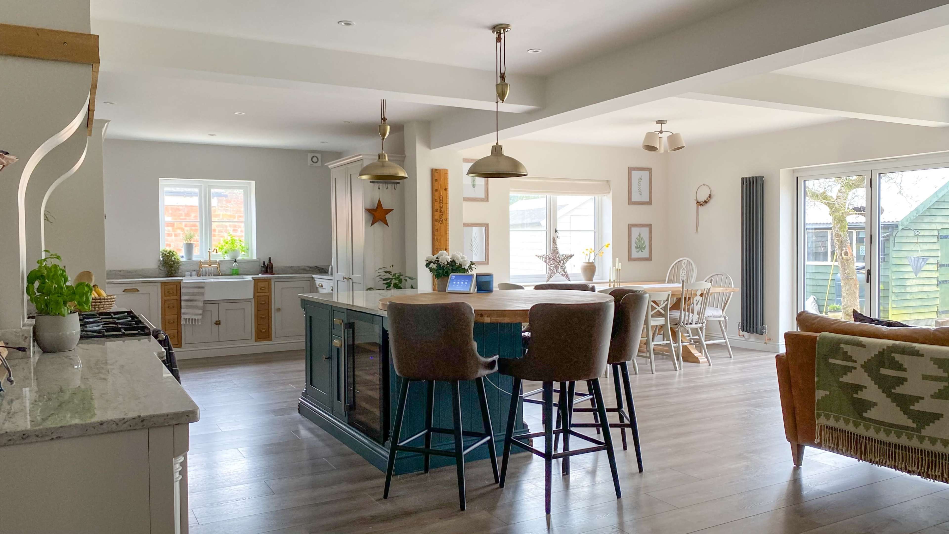 A modern open-concept kitchen and dining area with a central island, bar stools, and a large window providing natural light.