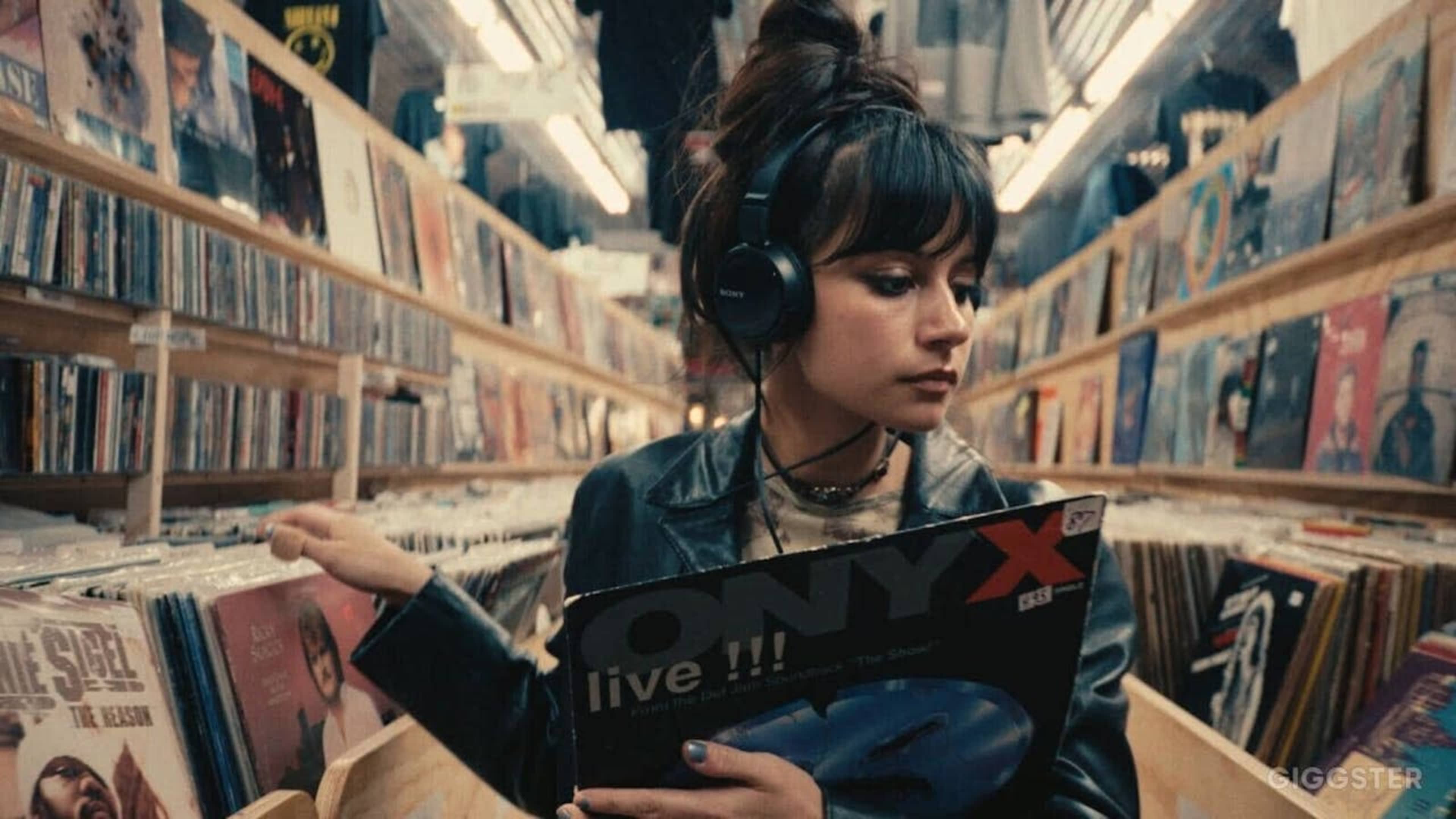 A young woman wearing headphones browses through vinyl records in a music store.