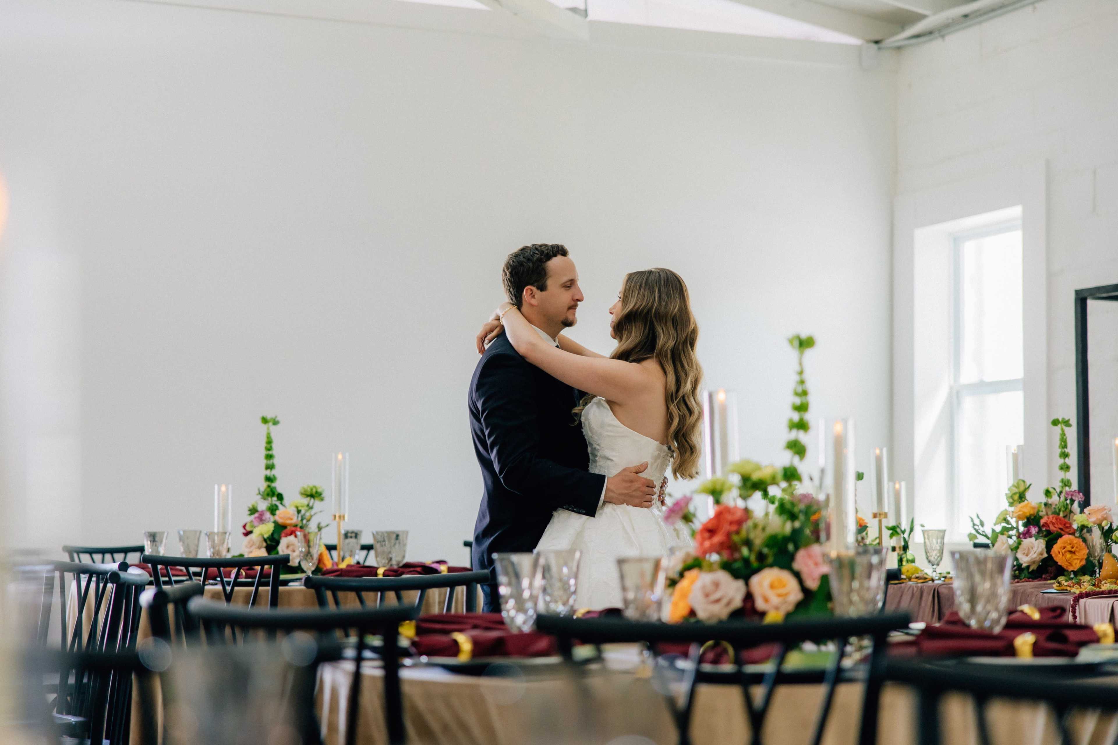A couple dances together in a decorated reception area with tables set for a wedding.