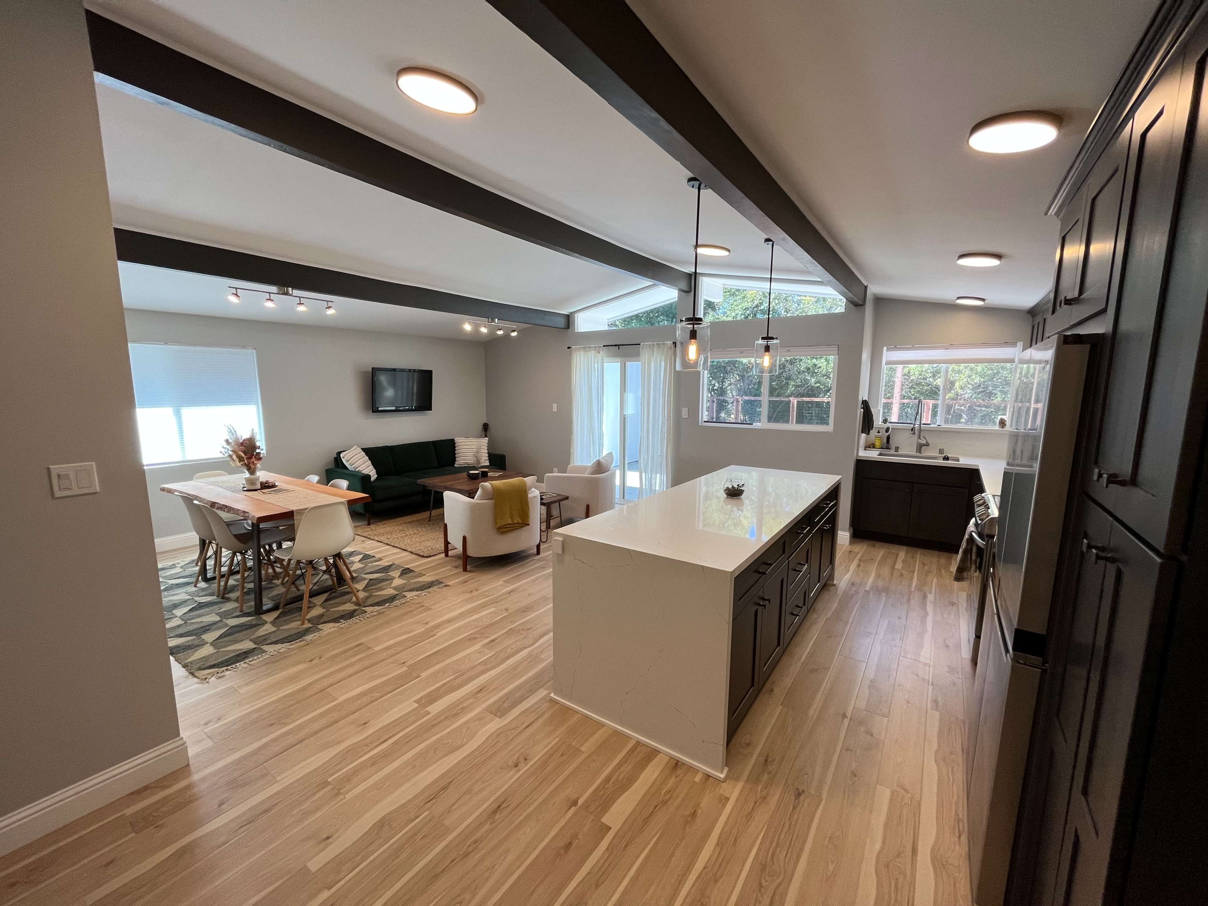 A modern open-concept living space with a kitchen island, dining area, and a sitting area featuring a sofa and chairs.