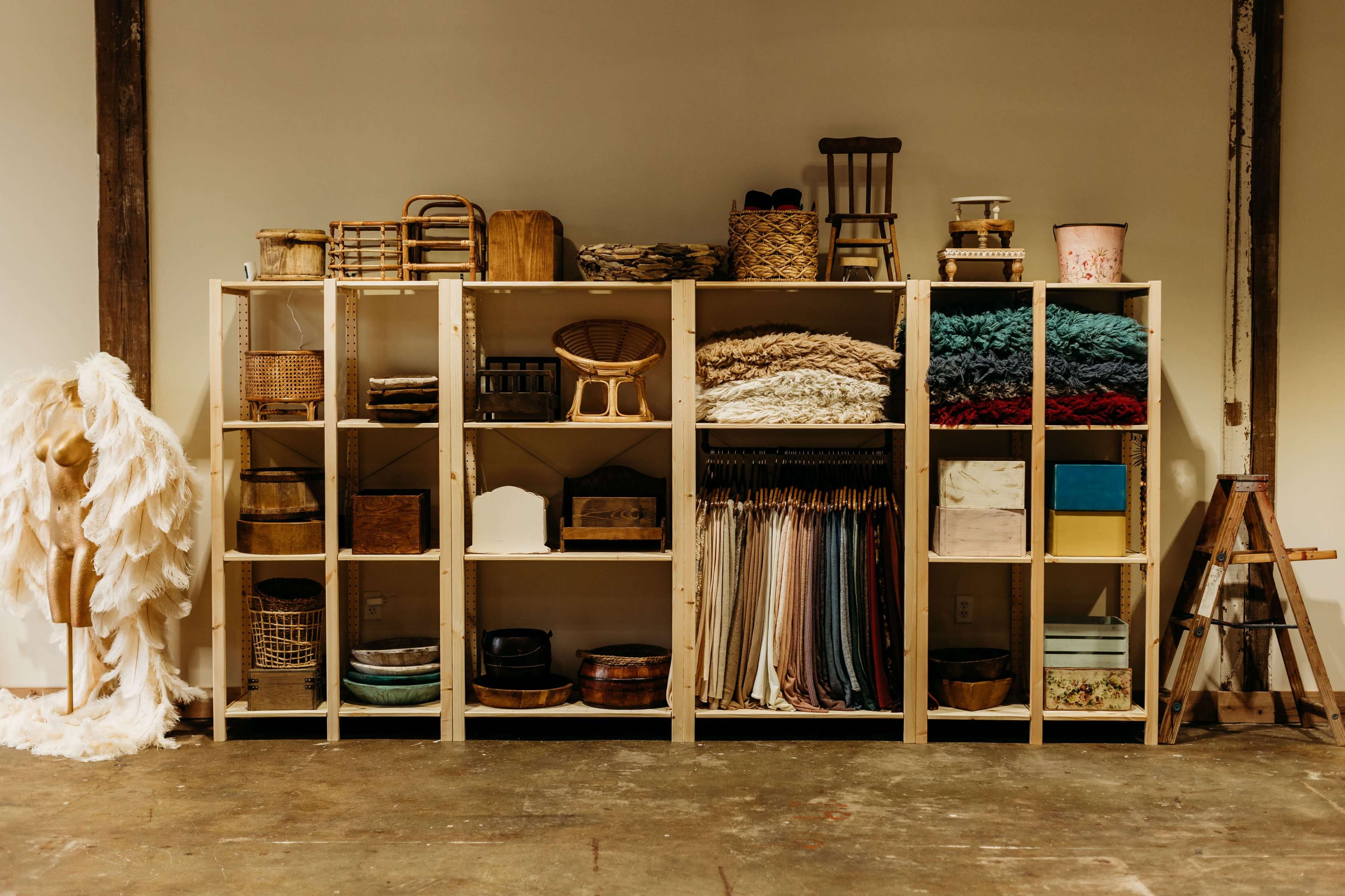 A wooden shelf is filled with various baskets, fabric rolls, and containers, arranged neatly against a plain wall.