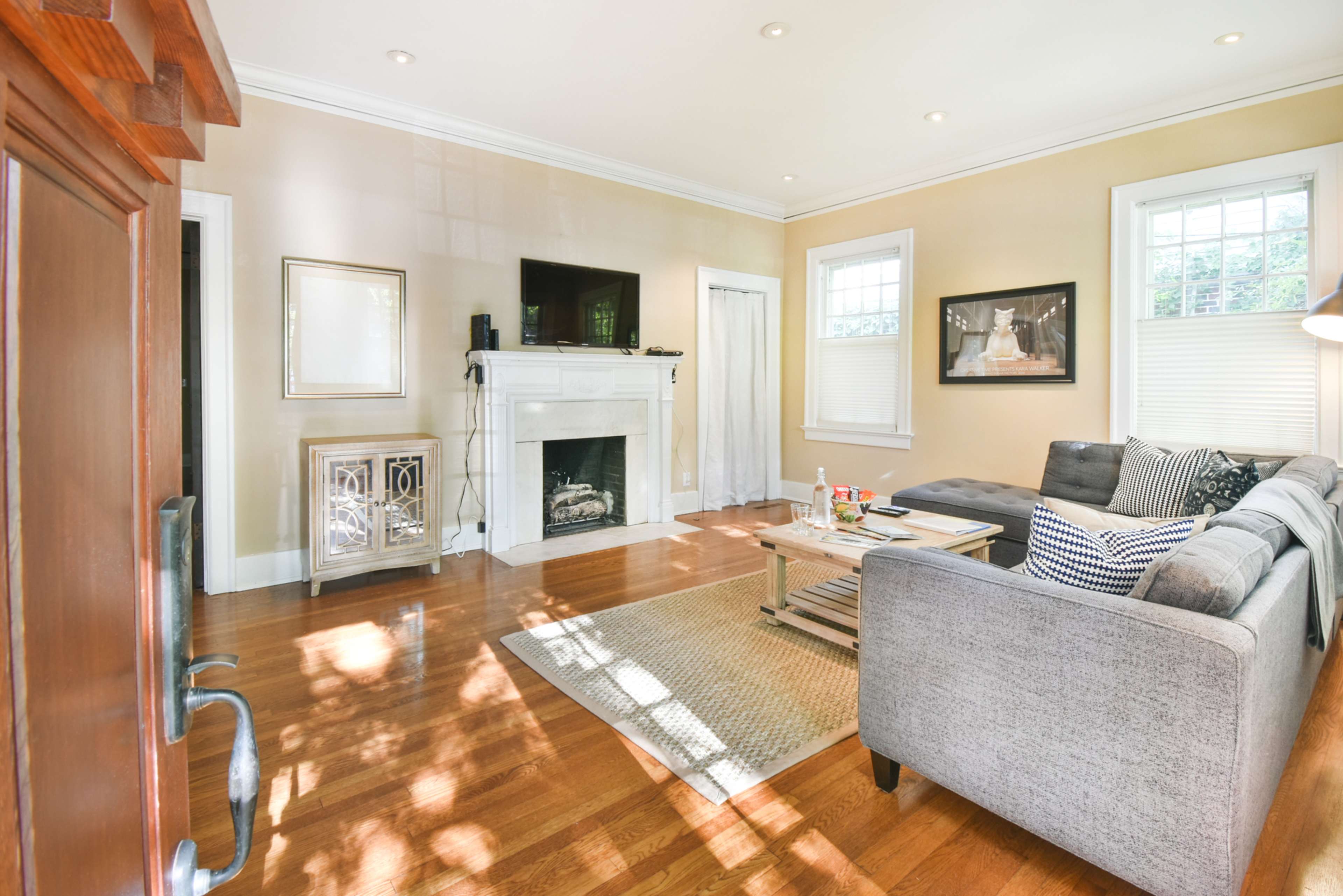 The living room features a gray sectional sofa, a wooden coffee table, and a fireplace with a television mounted above it.