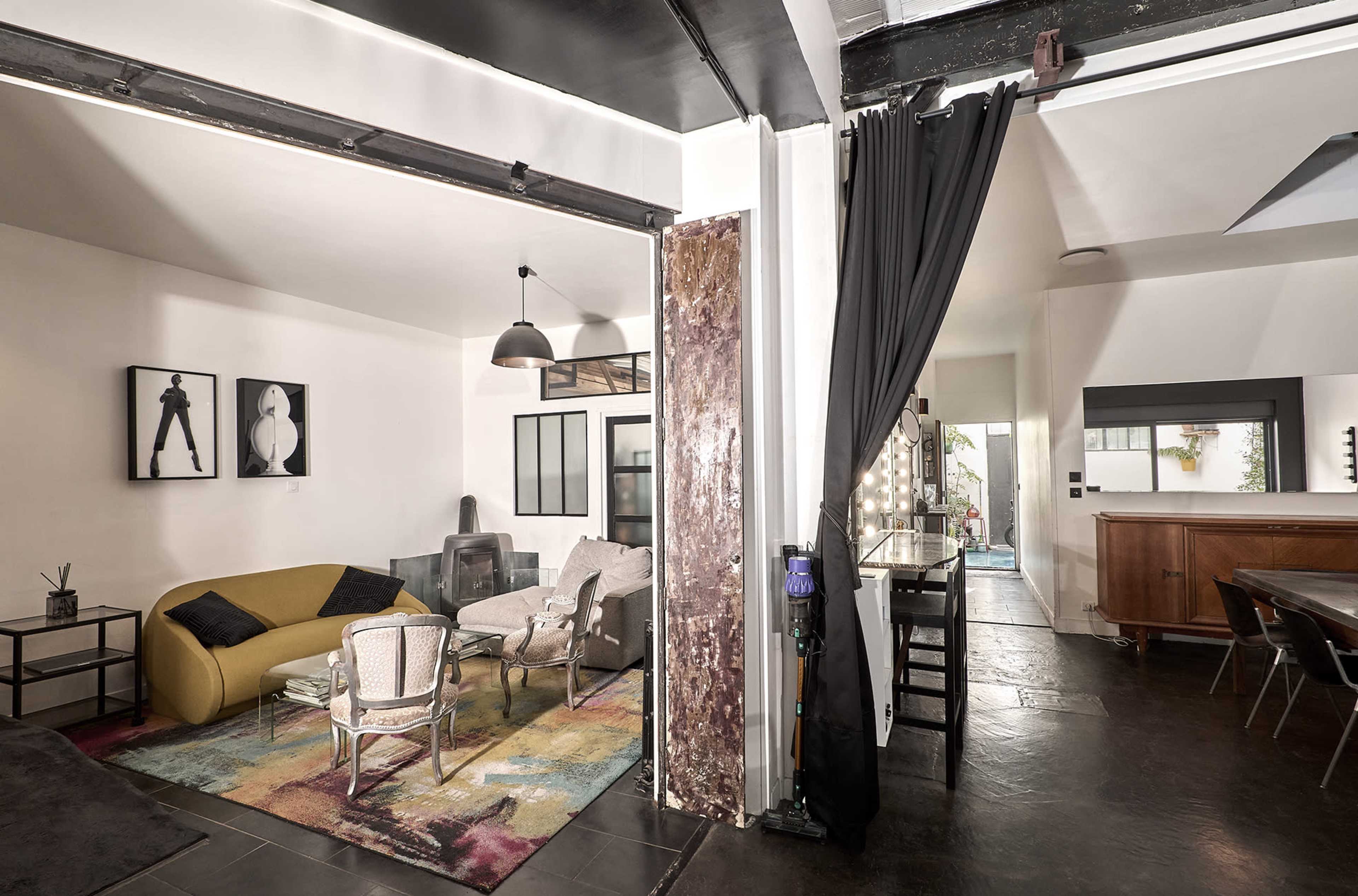 The image shows a modern, open-concept living space with a seating area, a dining area, and an outdoor view through a doorway.