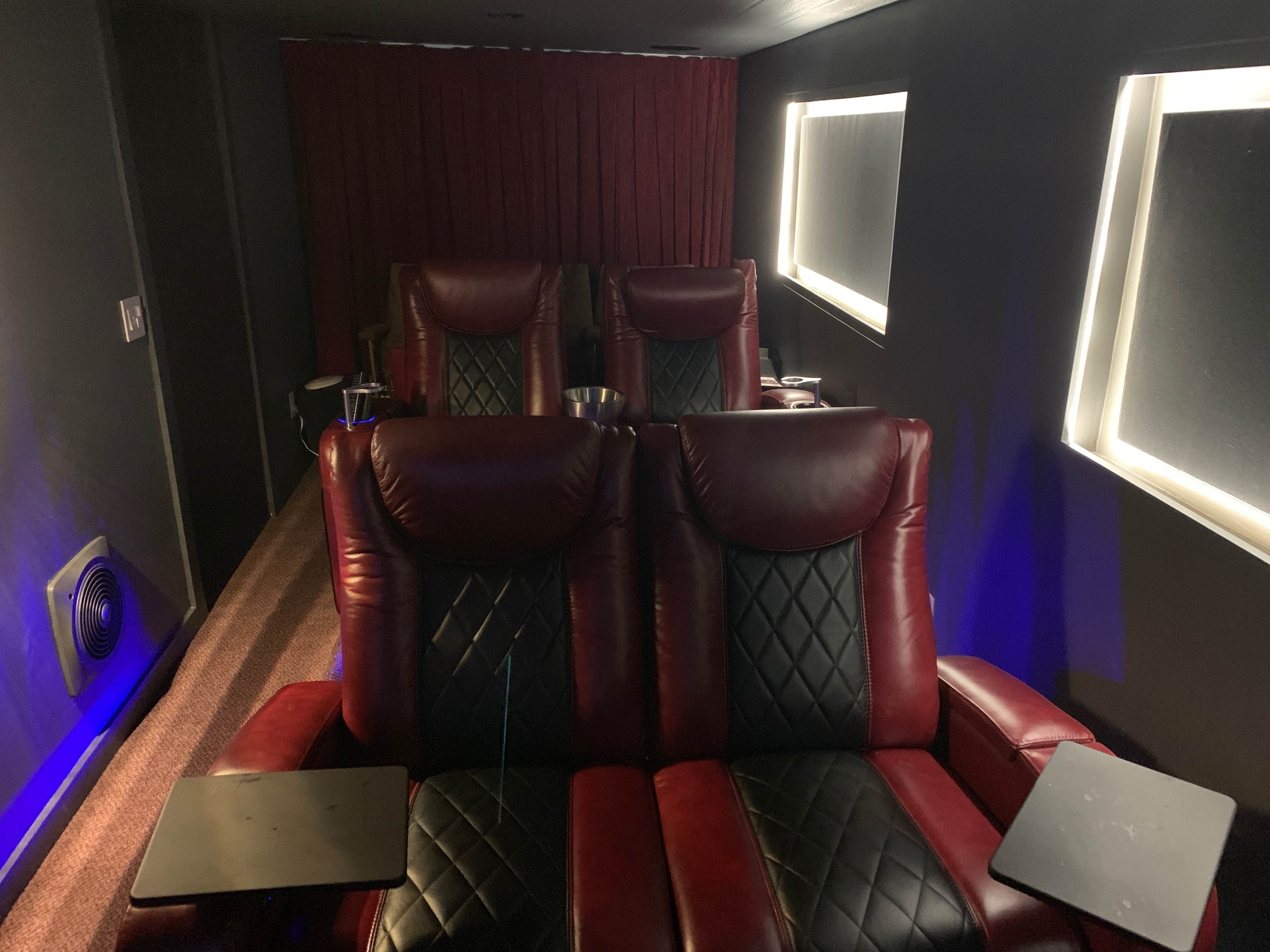 A dimly lit home theater with red reclining chairs and ambient lighting.