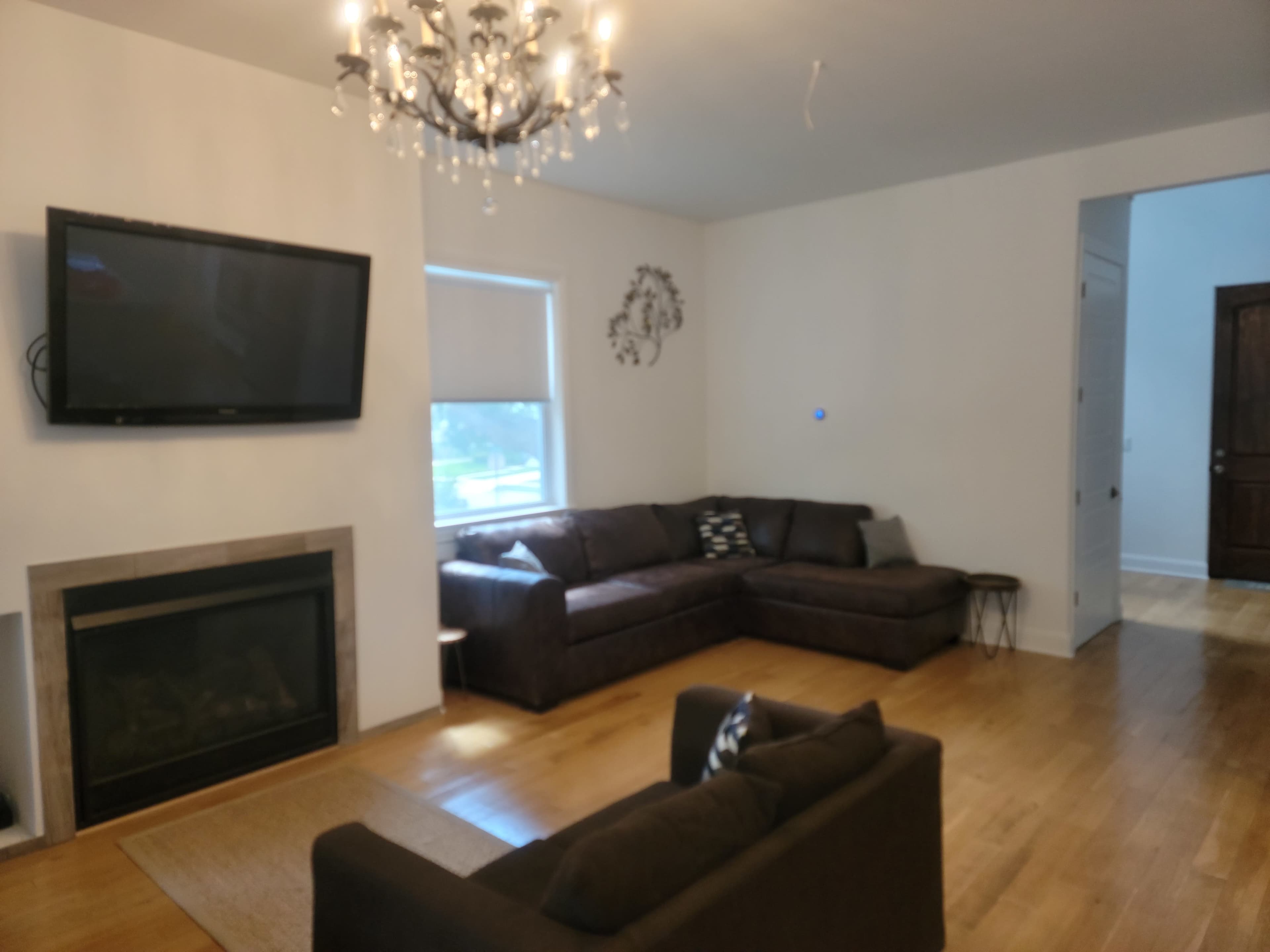 A living room with a sectional couch, a television mounted on the wall, a fireplace, and a small side table.