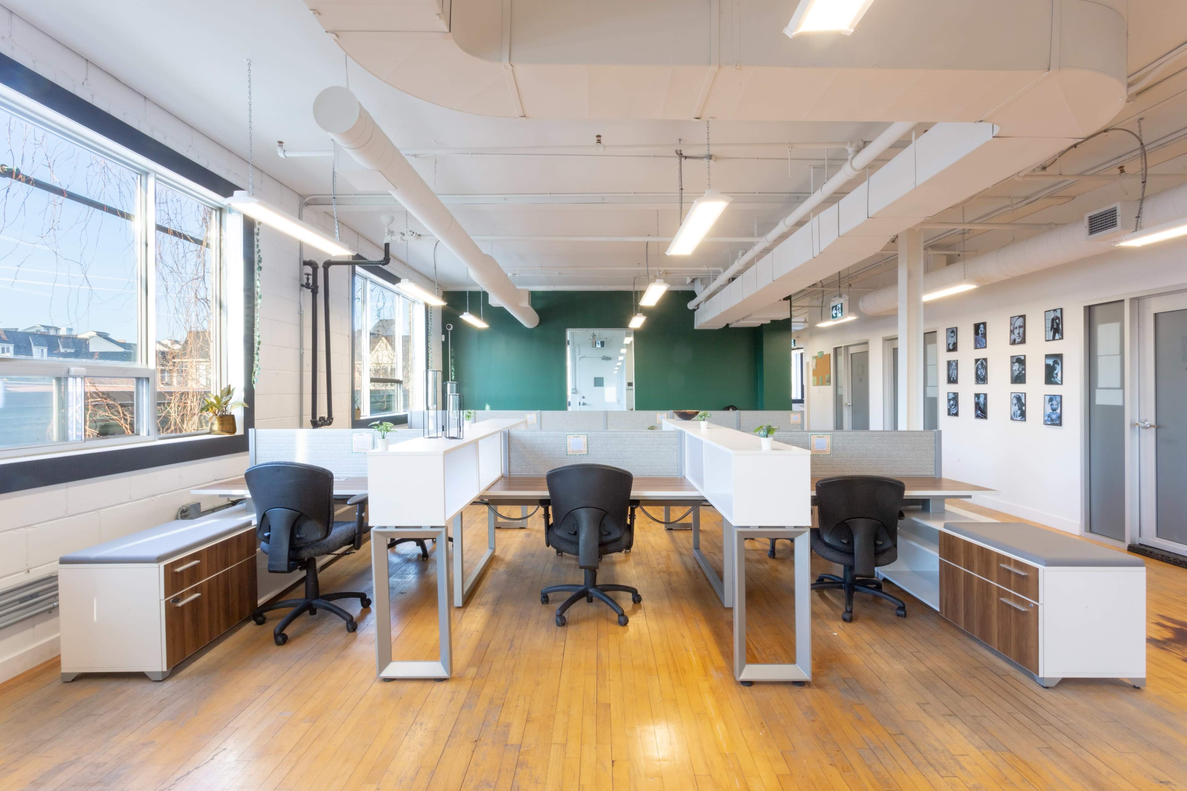 A well-lit office space with four modern workstations, each equipped with a desk, chair, and storage cabinets, arranged in a symmetrical layout.