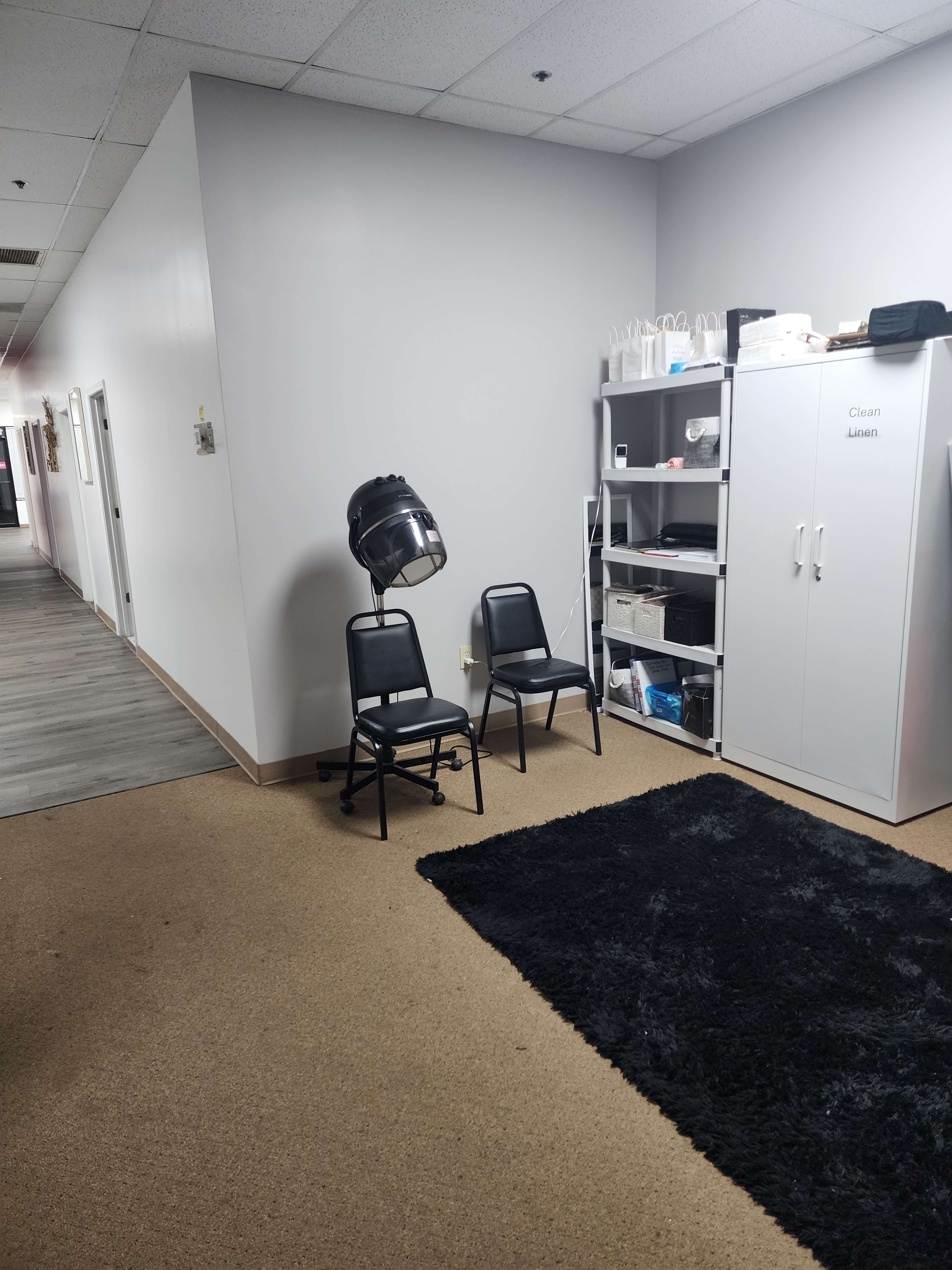 The image shows a hallway with gray walls, two black chairs next to a hairdryer, and a storage cabinet labeled "Clean Items" beside a shelf.
