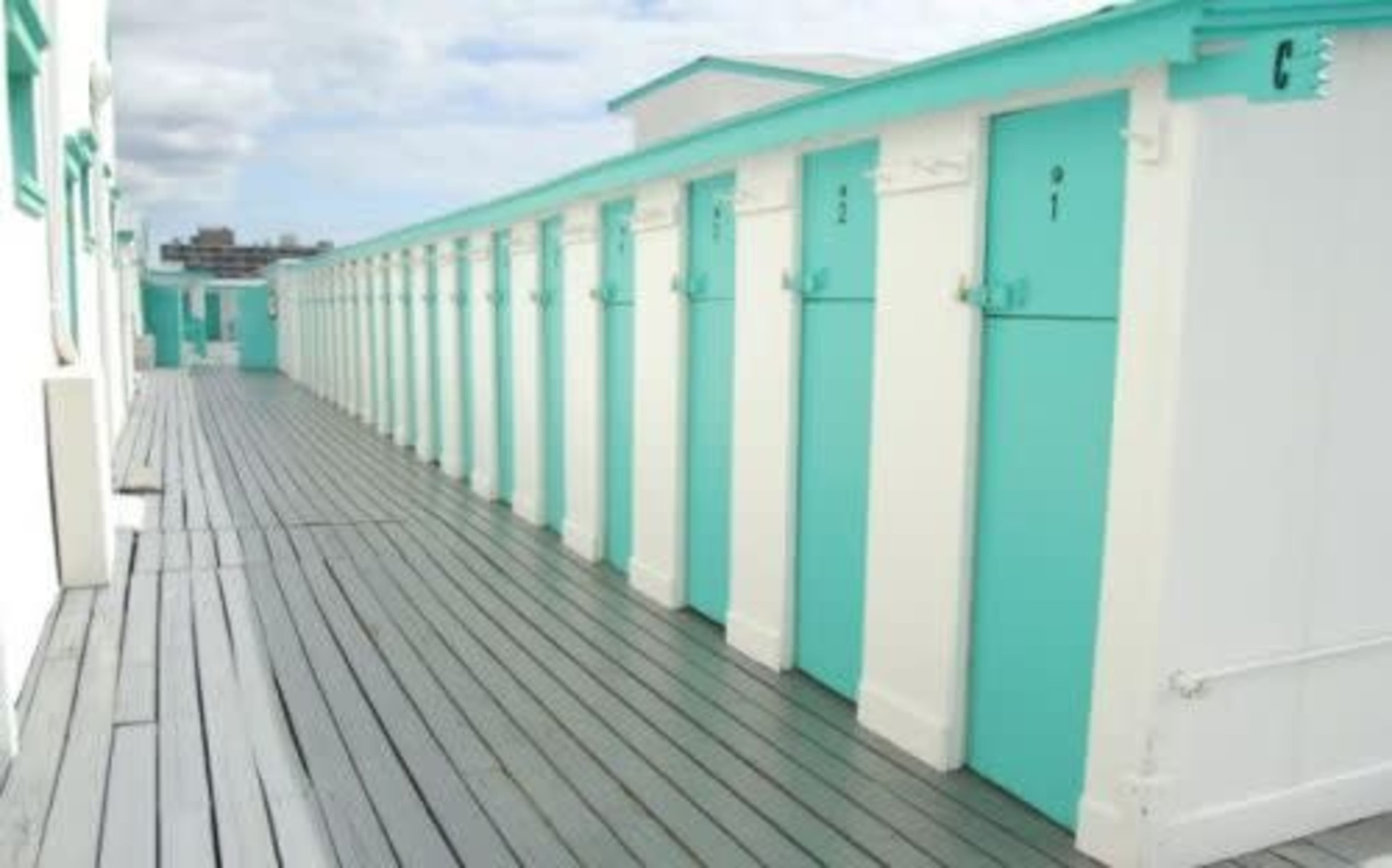 A row of turquoise and white storage units along a wooden deck.