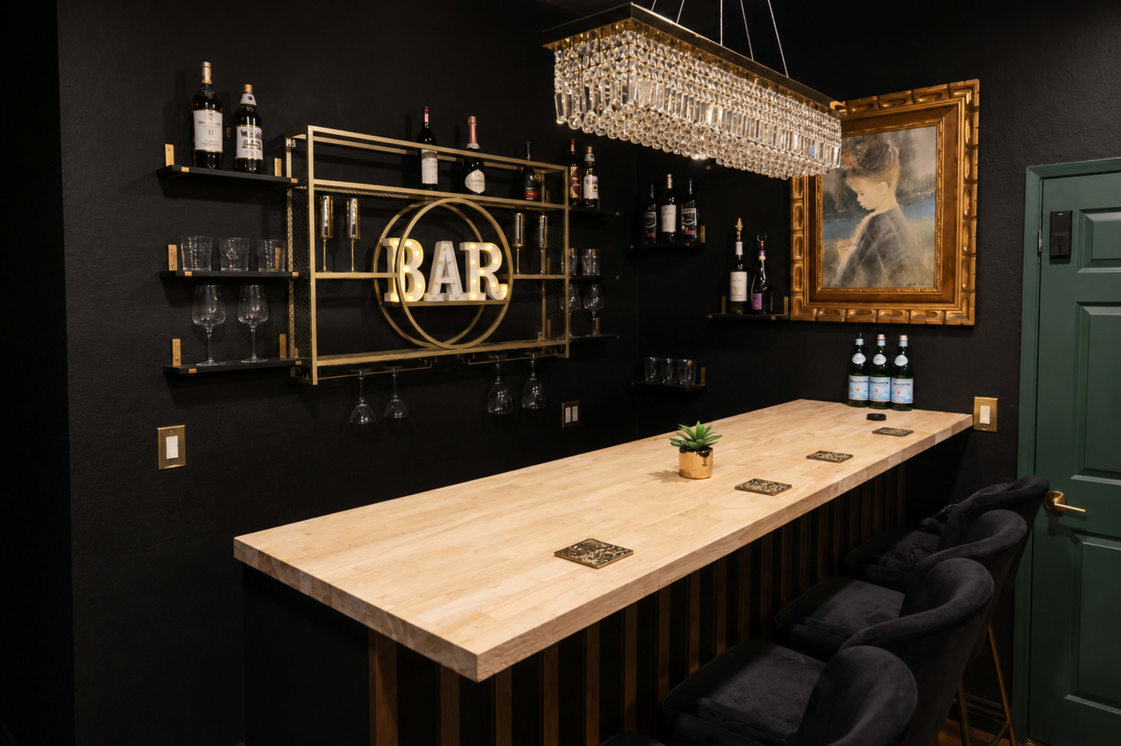 The image shows a modern home bar with a wooden countertop, a gold-framed sign that reads "BAR," and shelves displaying various bottles and glassware, set against a black wall.