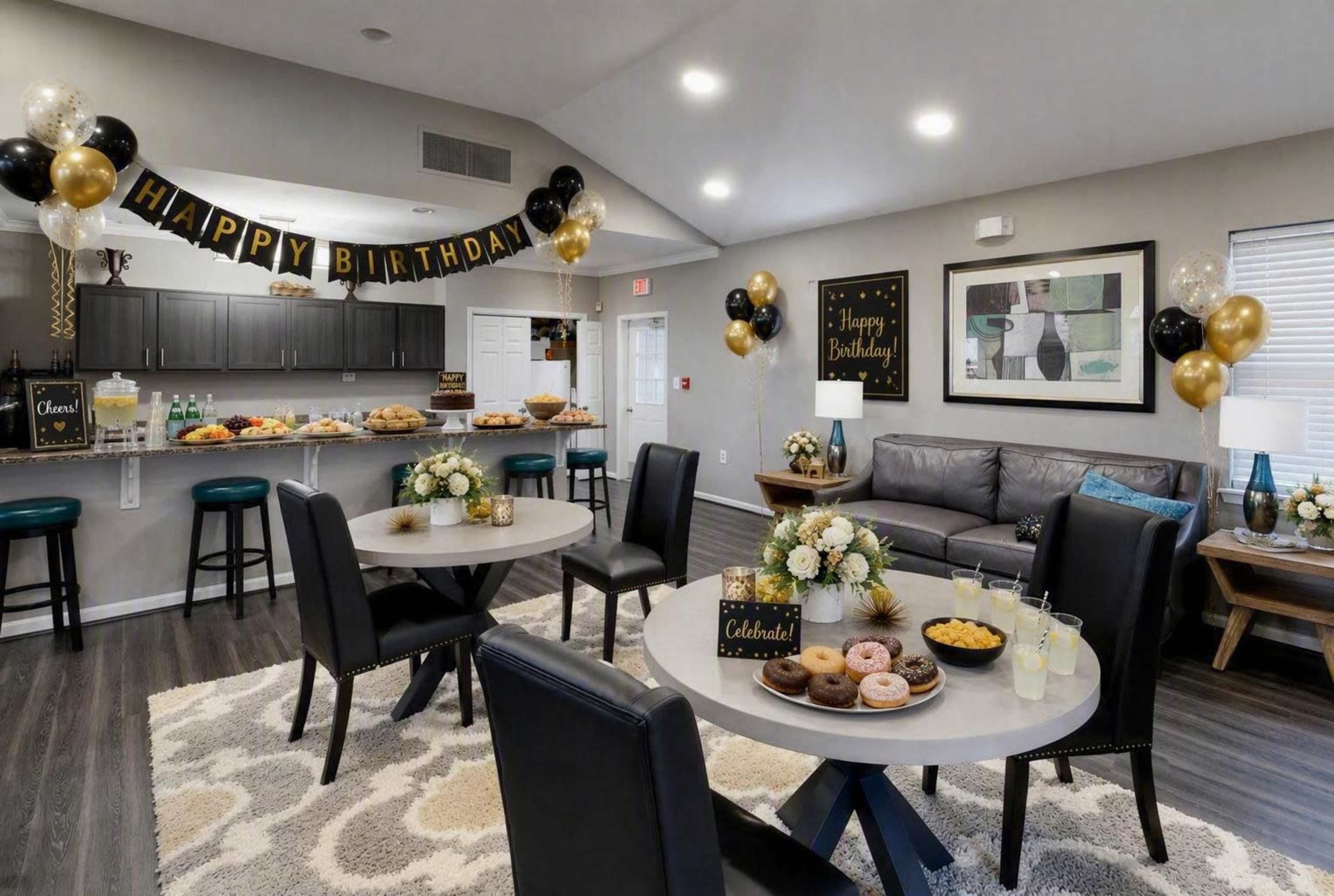 The image shows a decorated living space for a birthday celebration, featuring two dining tables with refreshments and snacks, along with a "Happy Birthday" banner and balloons.