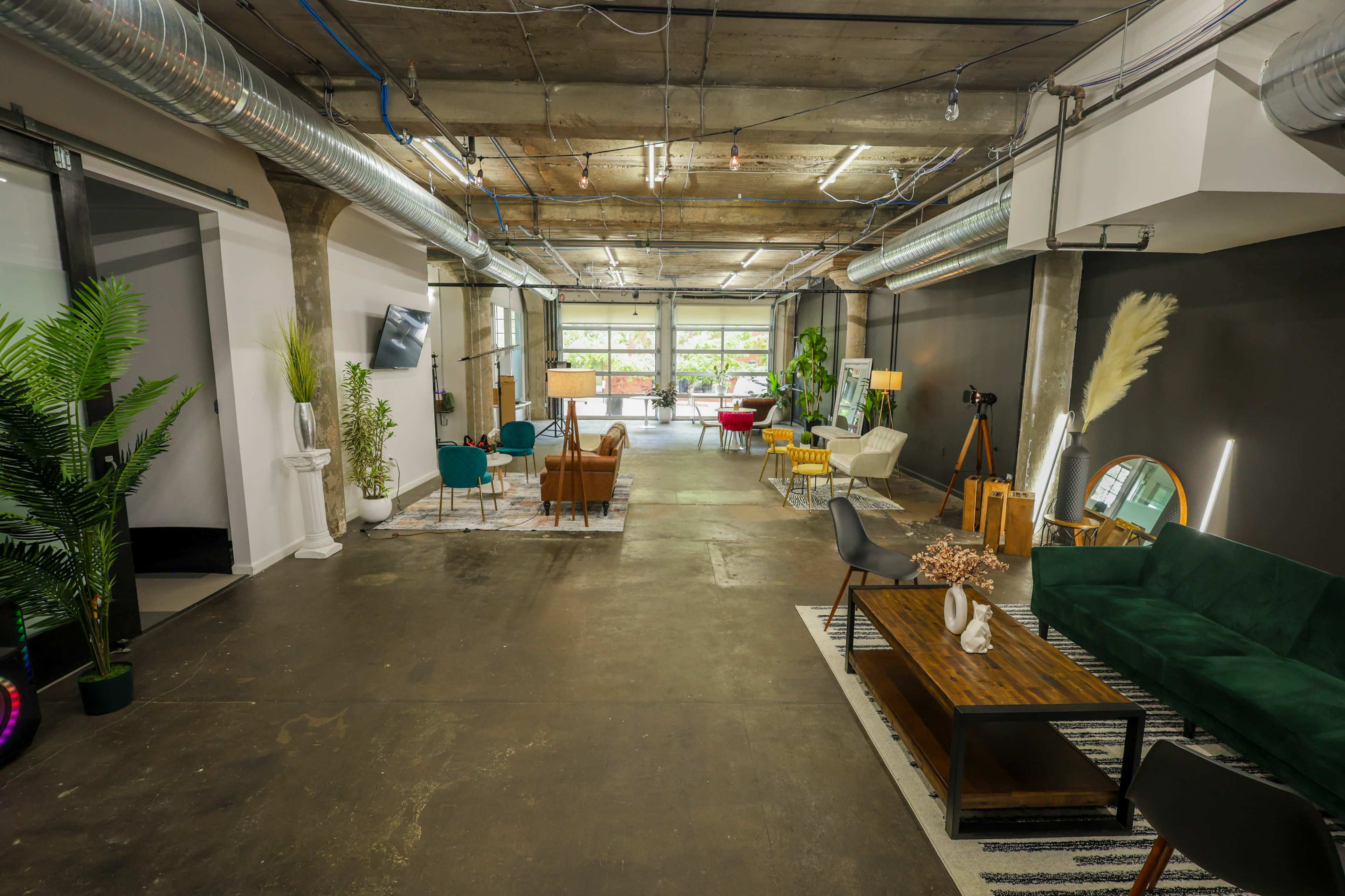 A spacious interior with concrete ceilings, modern furniture, and plants arranged in a well-lit area.