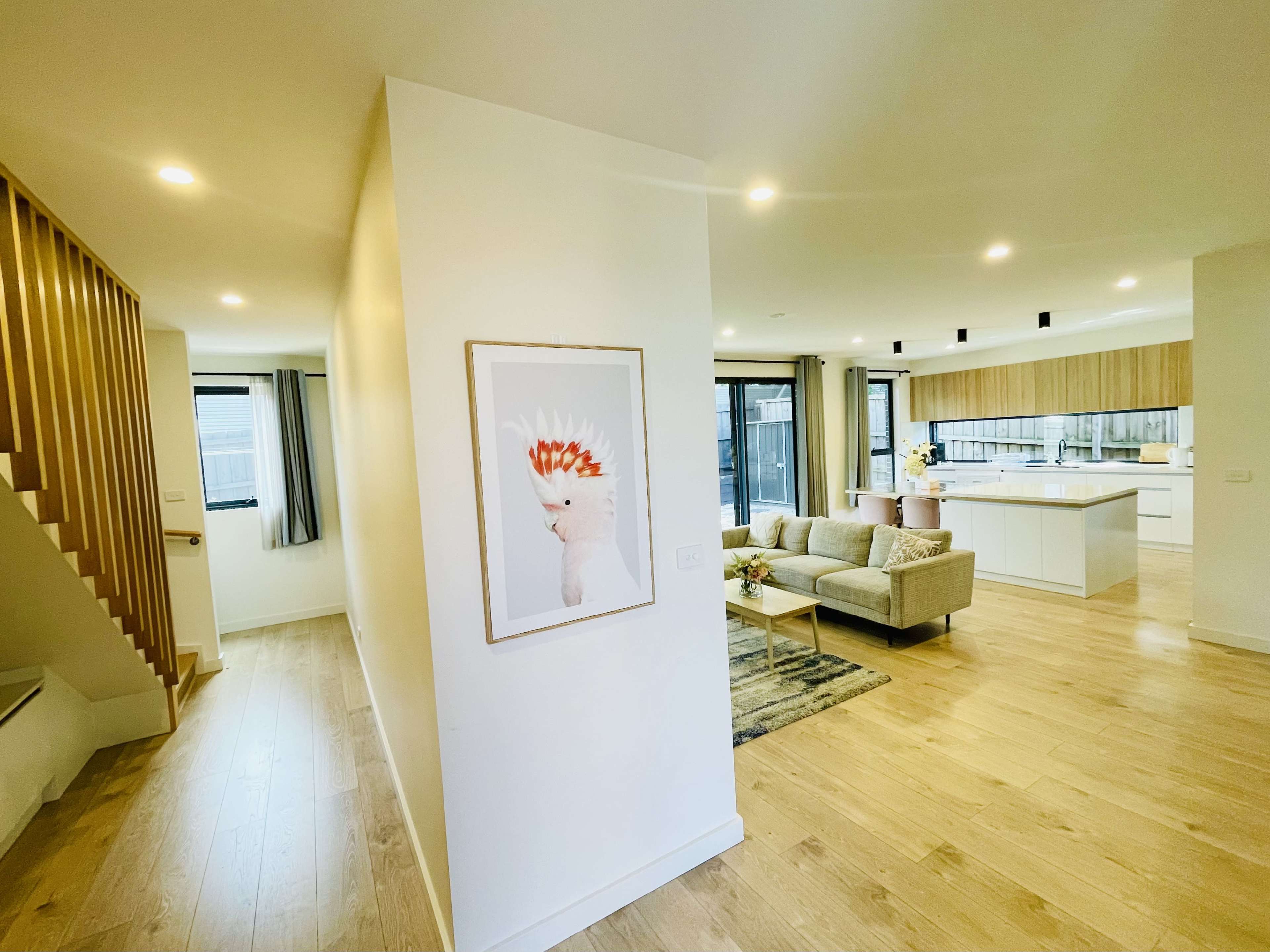 A modern interior with a hallway leading to an open living area that includes a kitchen and a seating space.