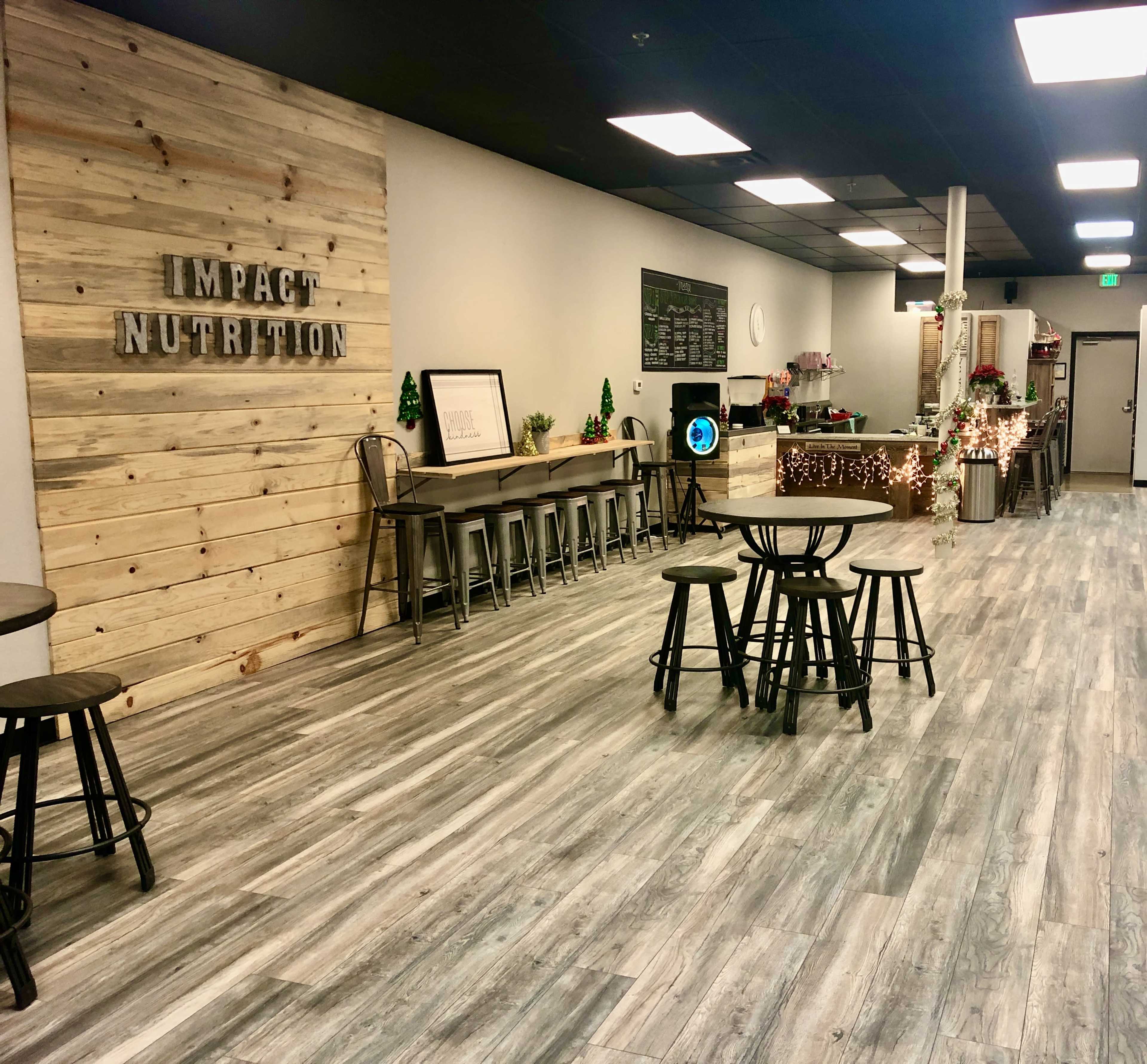 A clean, modern nutrition bar features wooden accents, high stools along a counter, and festive decorations across a spacious area.