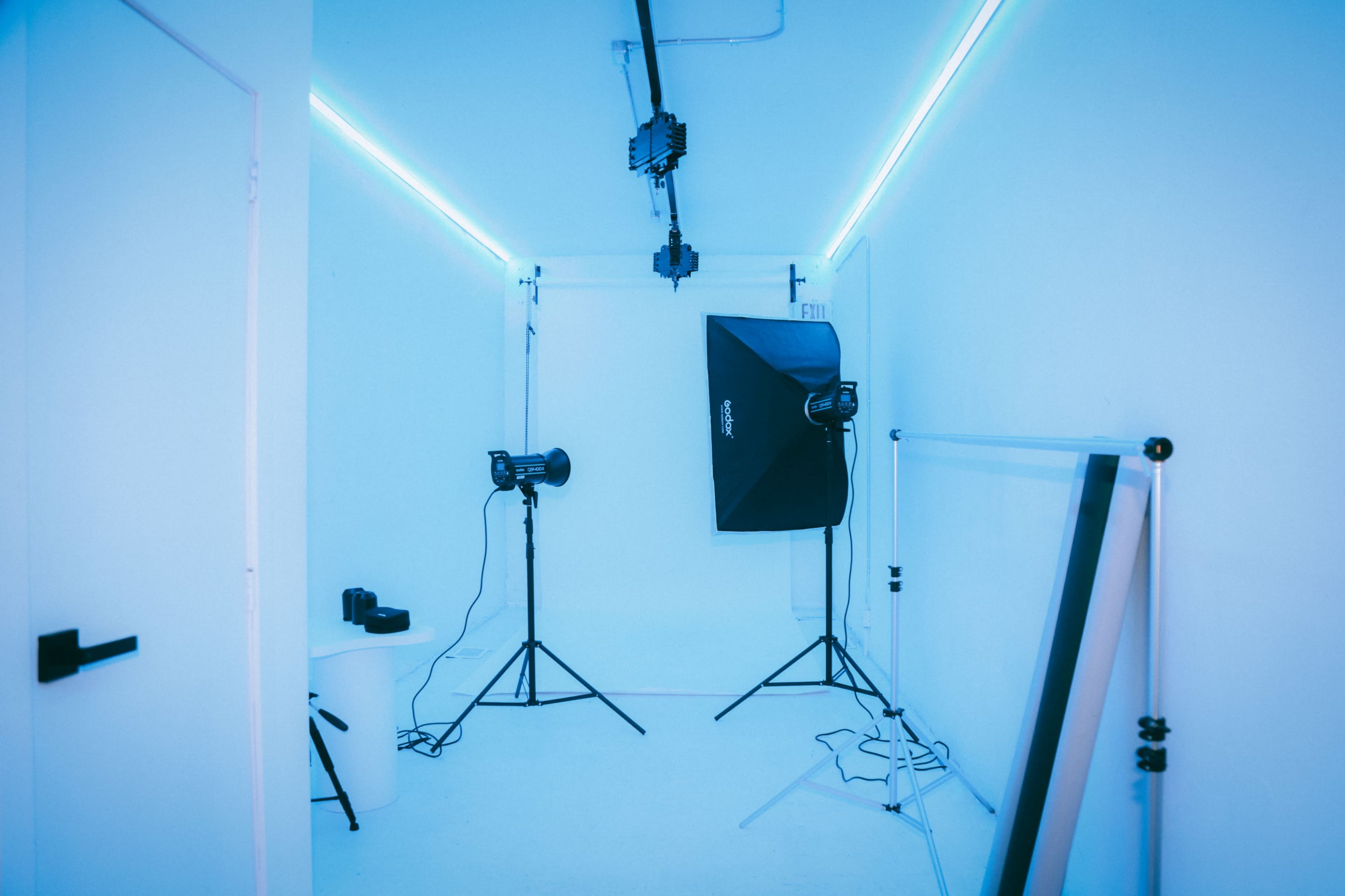 A photo studio with soft lighting, equipped with a backdrop, light stands, and various photography equipment.
