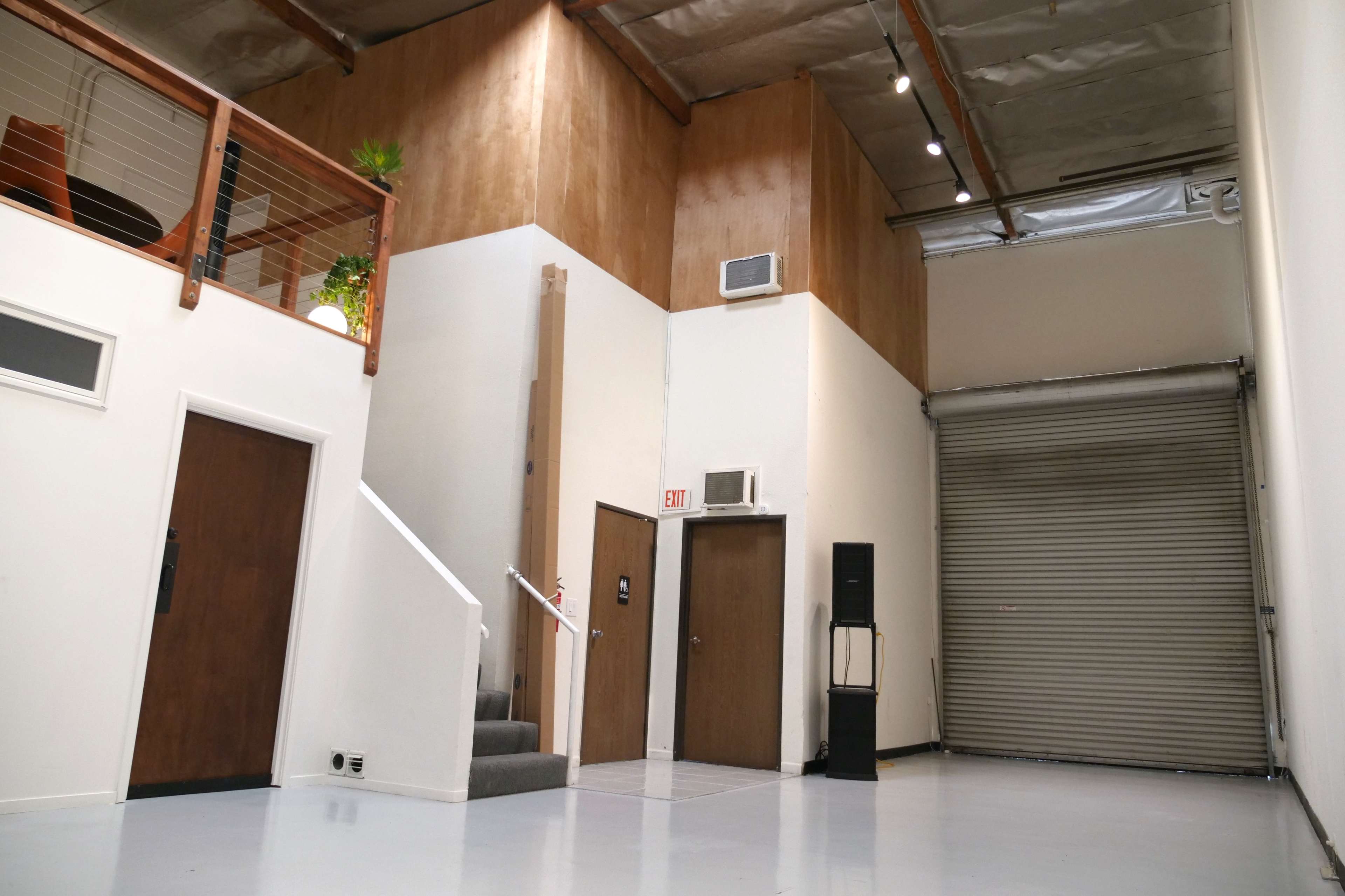 A spacious interior with a staircase leading to an upper level, a closed rolling door on the right, and various features typical of a commercial space.