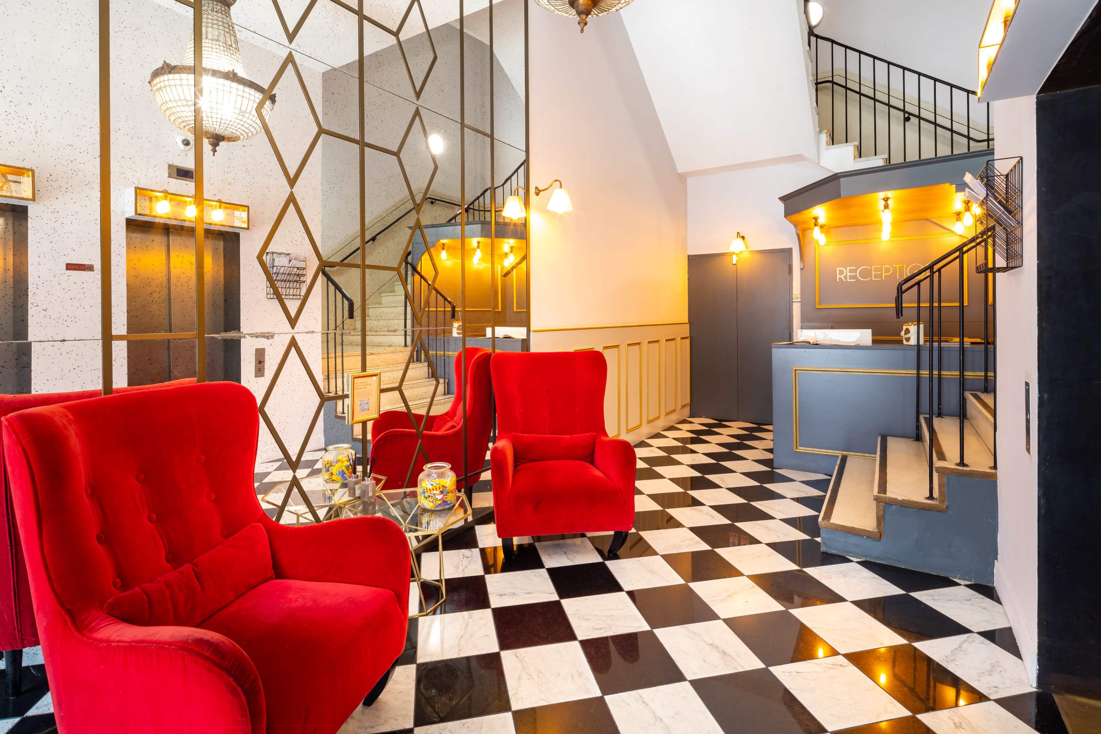 A luxurious hotel lobby with red armchairs, a checkered tiled floor, and a reception desk illuminated by warm lights.