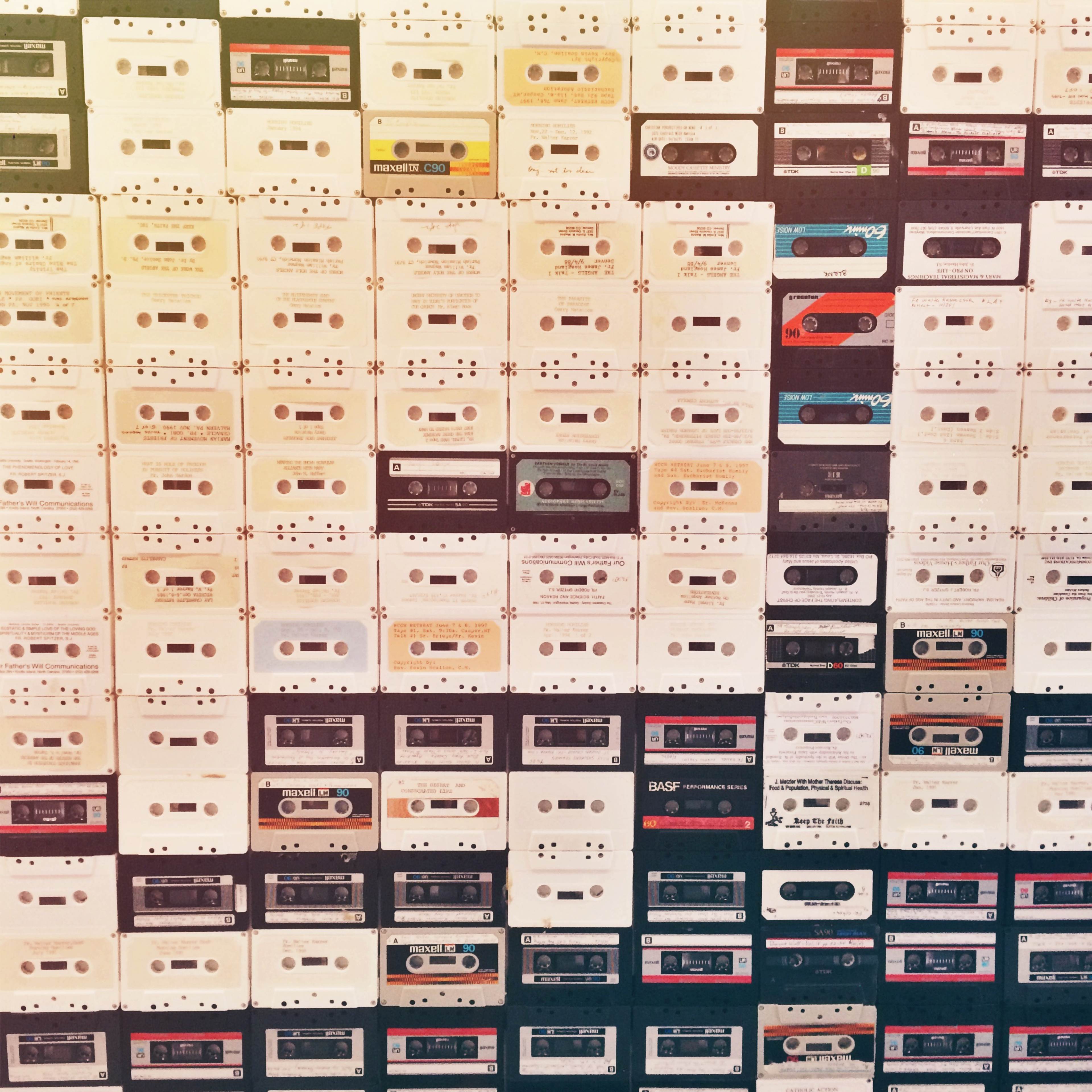 A wall densely covered with various cassette tapes arranged in a grid pattern.