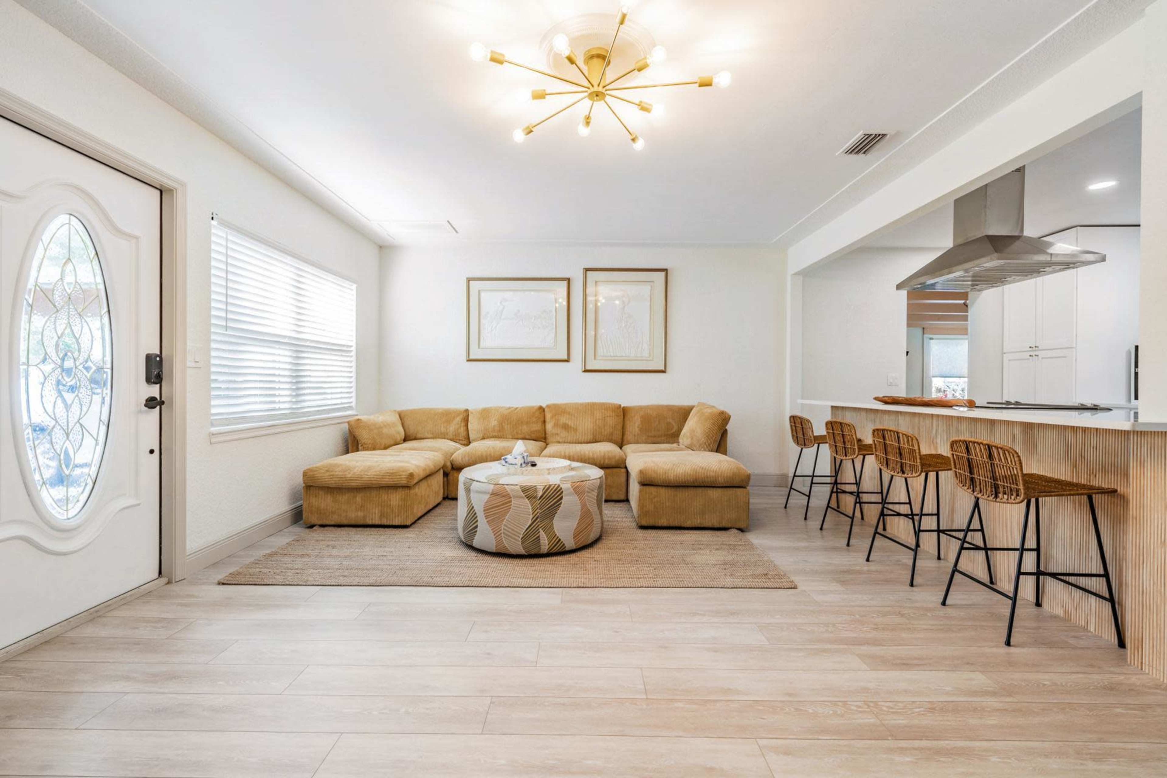 A modern living room featuring a large sectional couch, a round coffee table, and a bar area with high stools.
