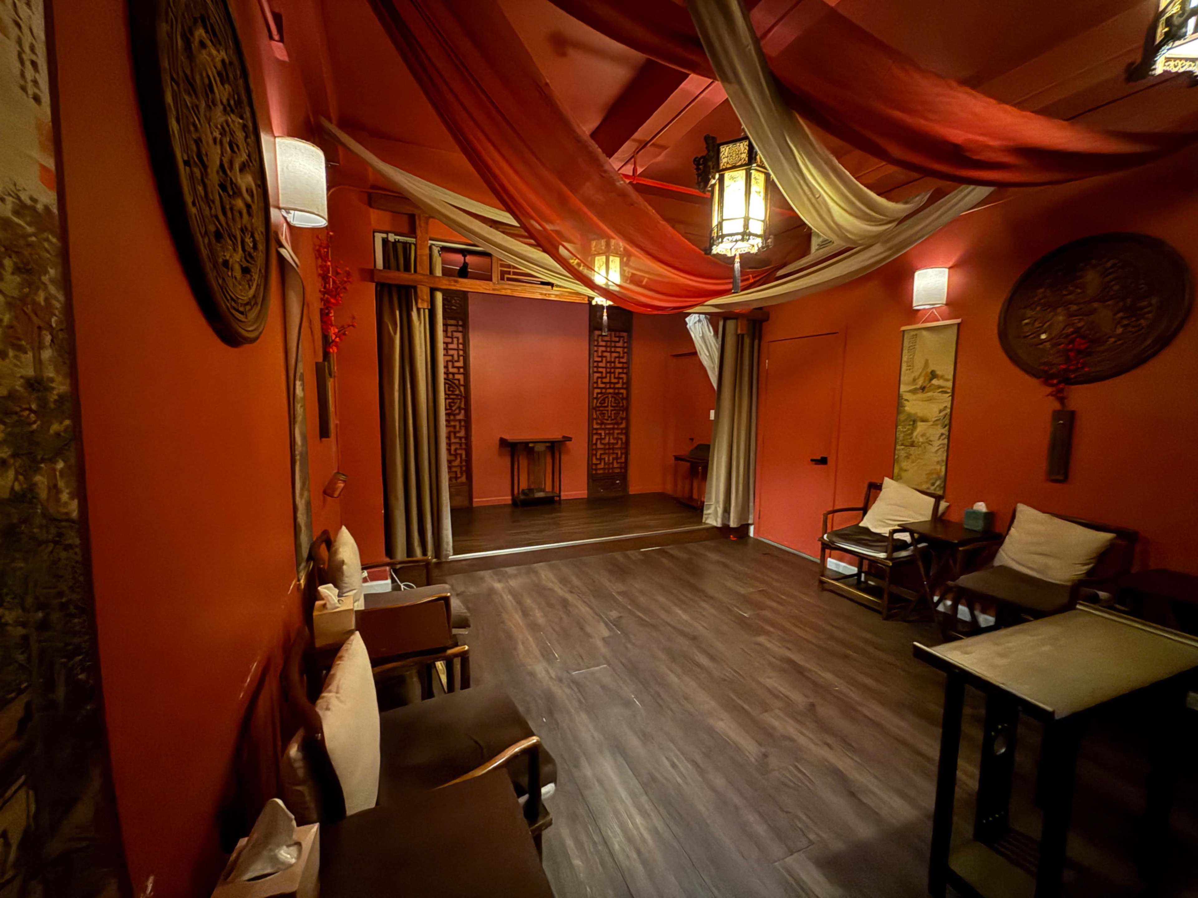 The image shows a warmly colored room with decorative drapes, wooden furniture, and art on the walls, creating a cozy atmosphere.