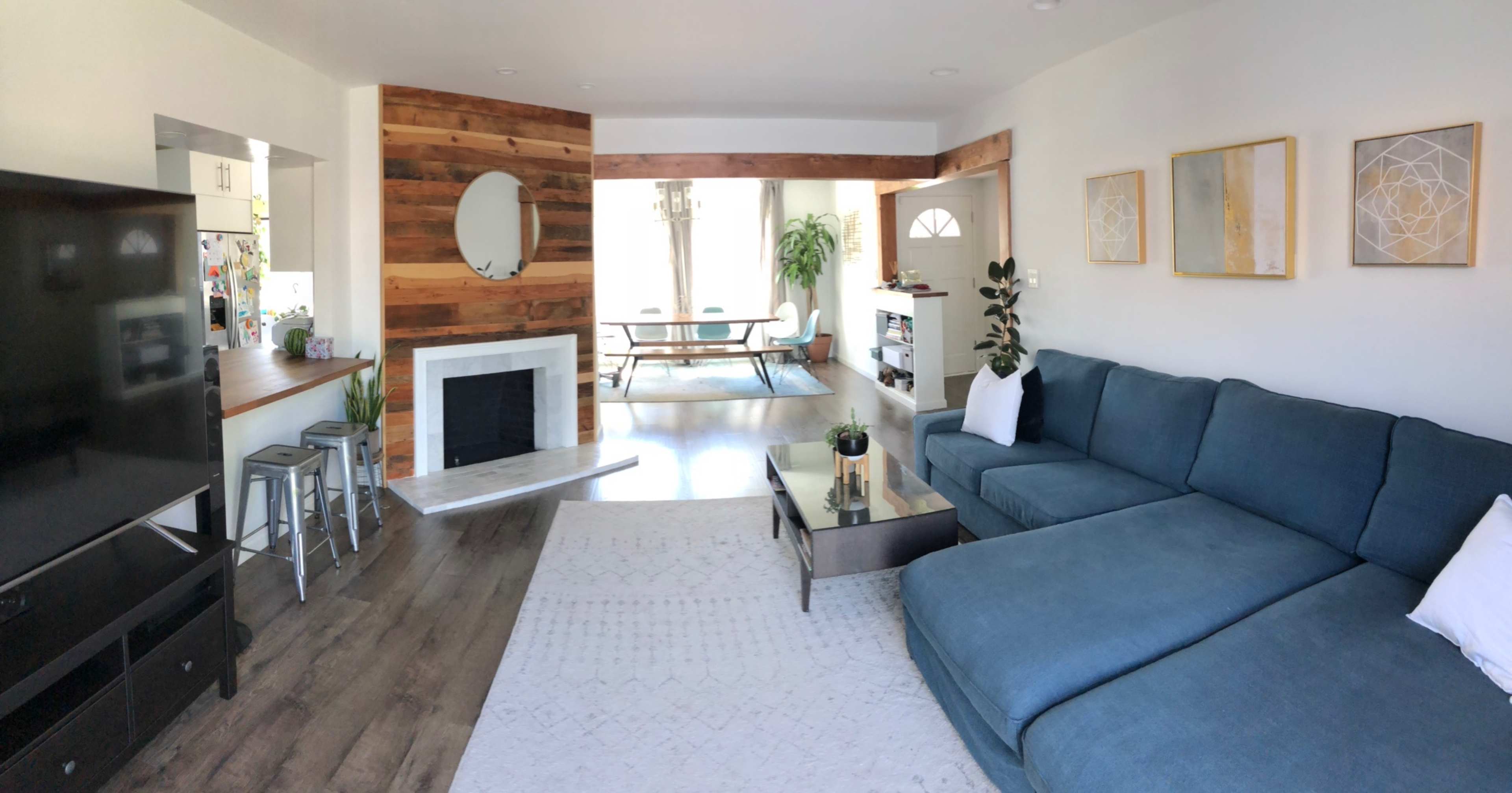 A modern living room with a blue sectional sofa, a coffee table, a fireplace, and sliding doors leading to an outdoor dining area.