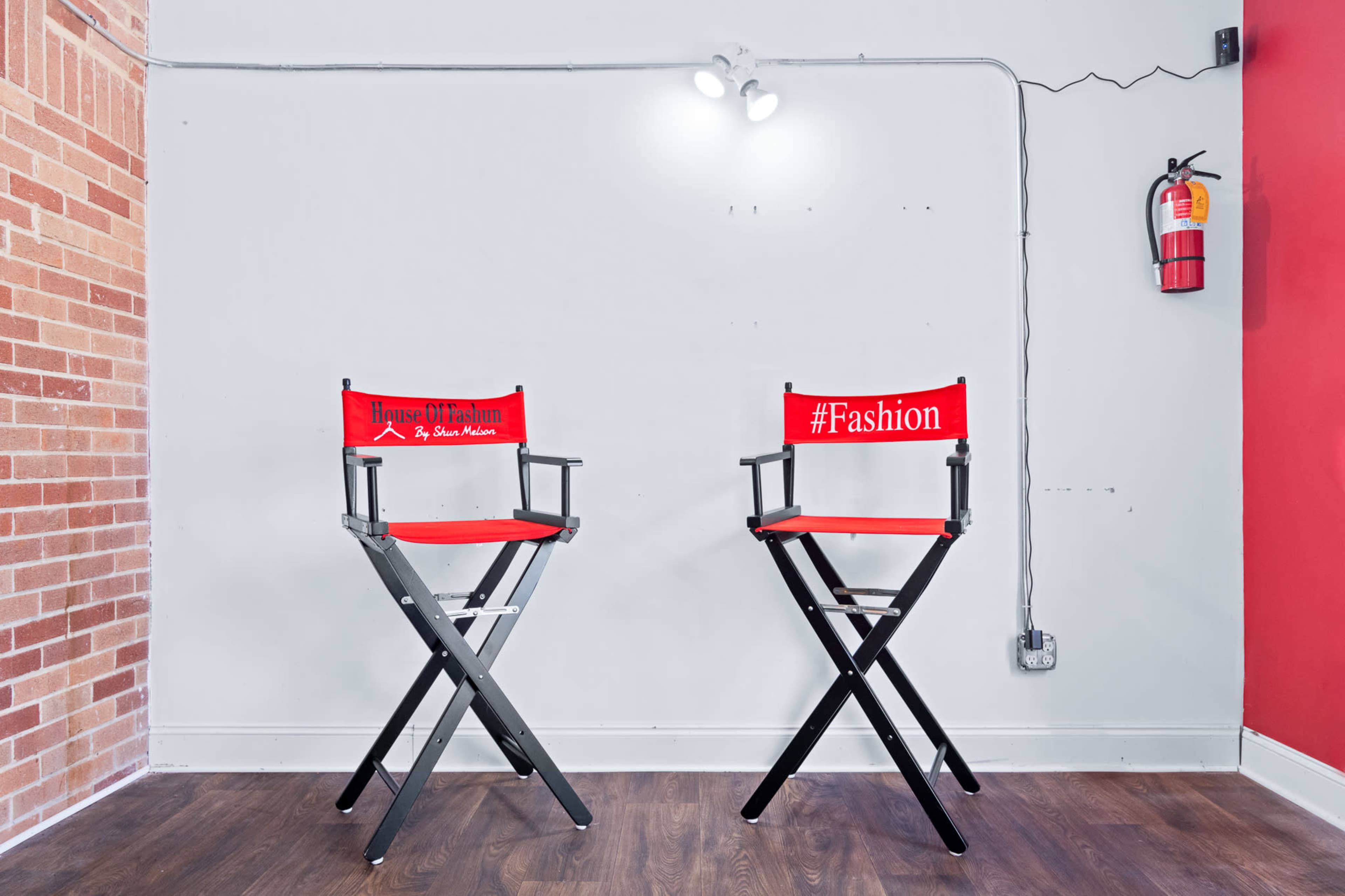 Two red director's chairs with labels, "House of Fashion" and "#Fashion," are positioned against a light gray wall in a minimalist setting.