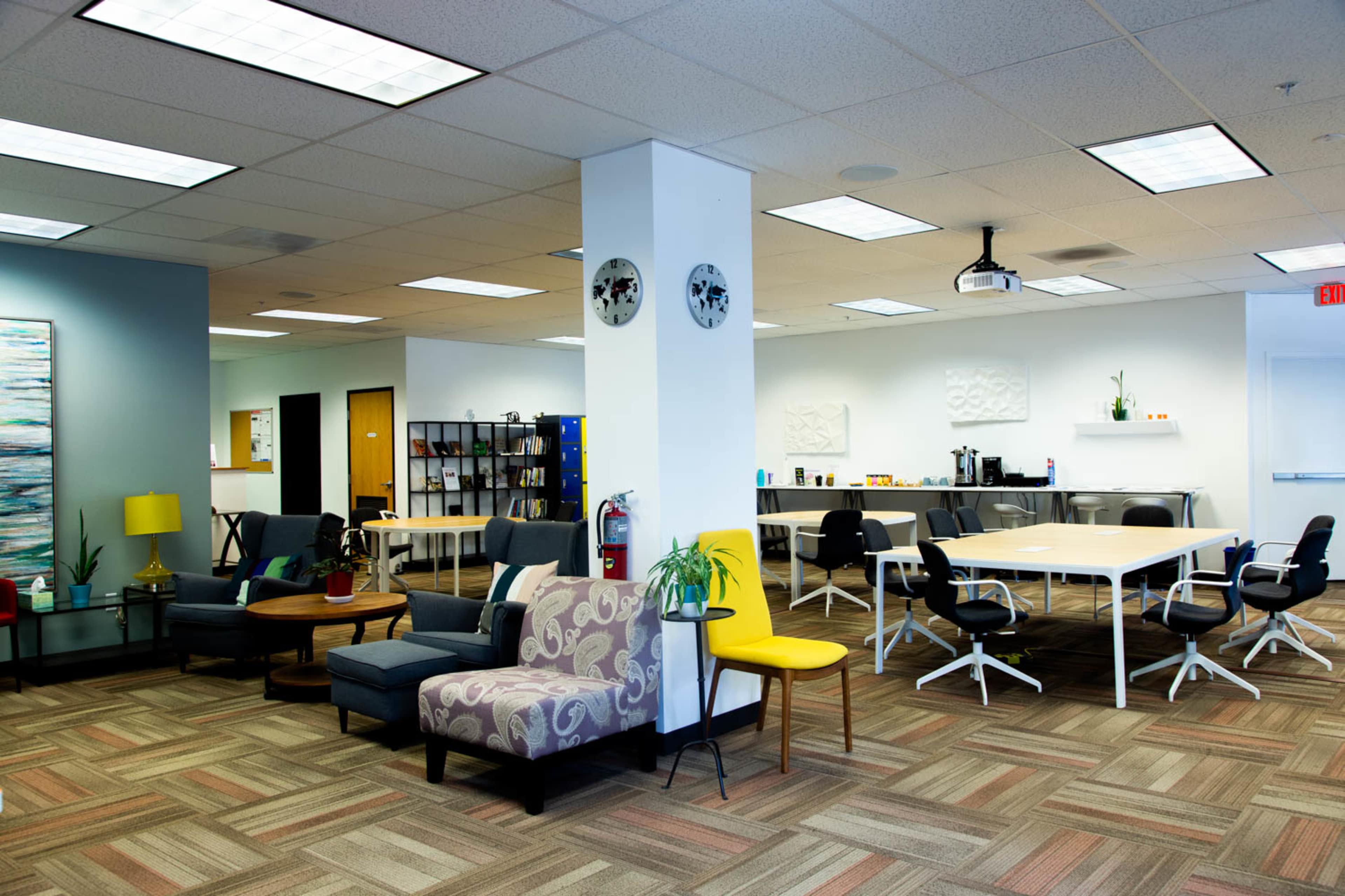 A modern office space featuring a lounge area with comfortable seating and a configuration of tables and chairs in an open layout.