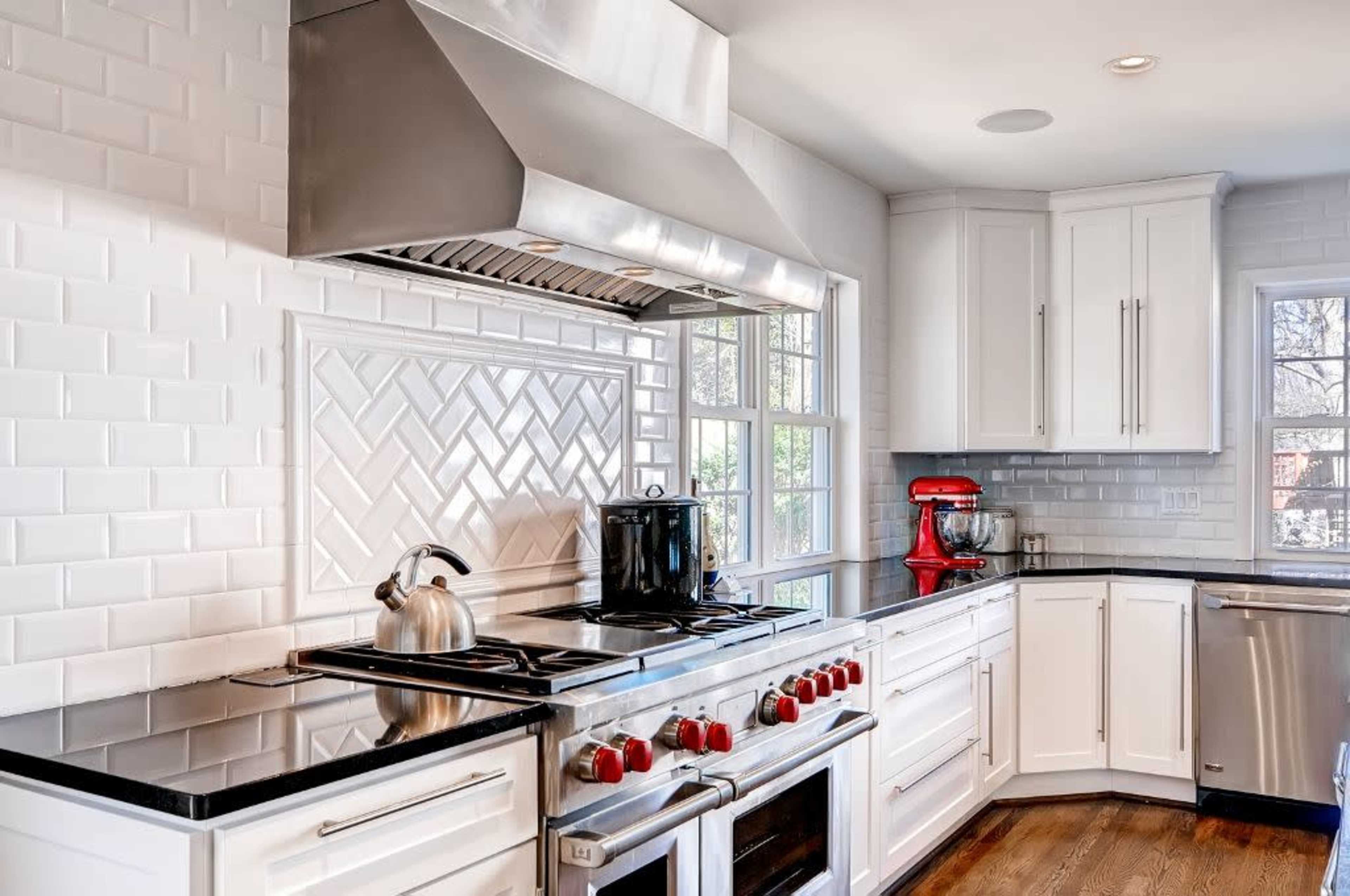 The kitchen features stainless steel appliances, a black countertop, and white cabinetry with a tiled backsplash.