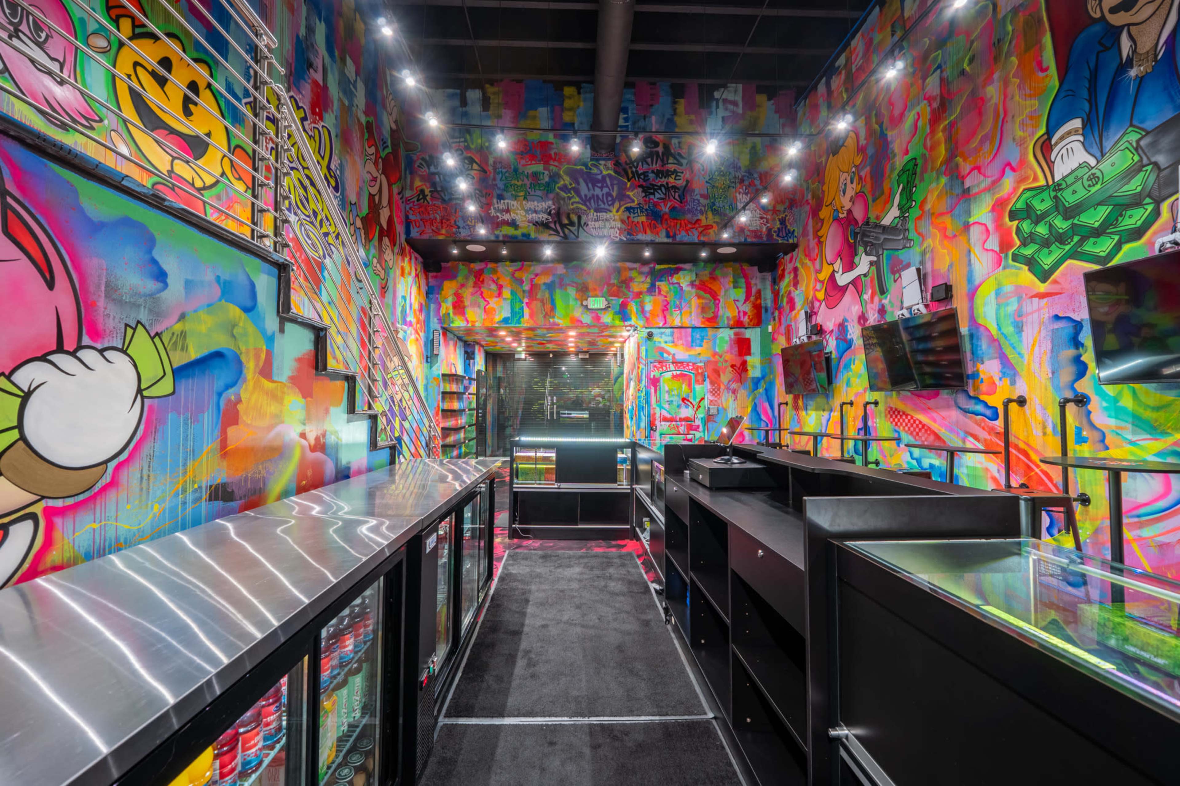 The image shows a vibrant, graffiti-covered retail space featuring black display counters and mirrors along the walls.