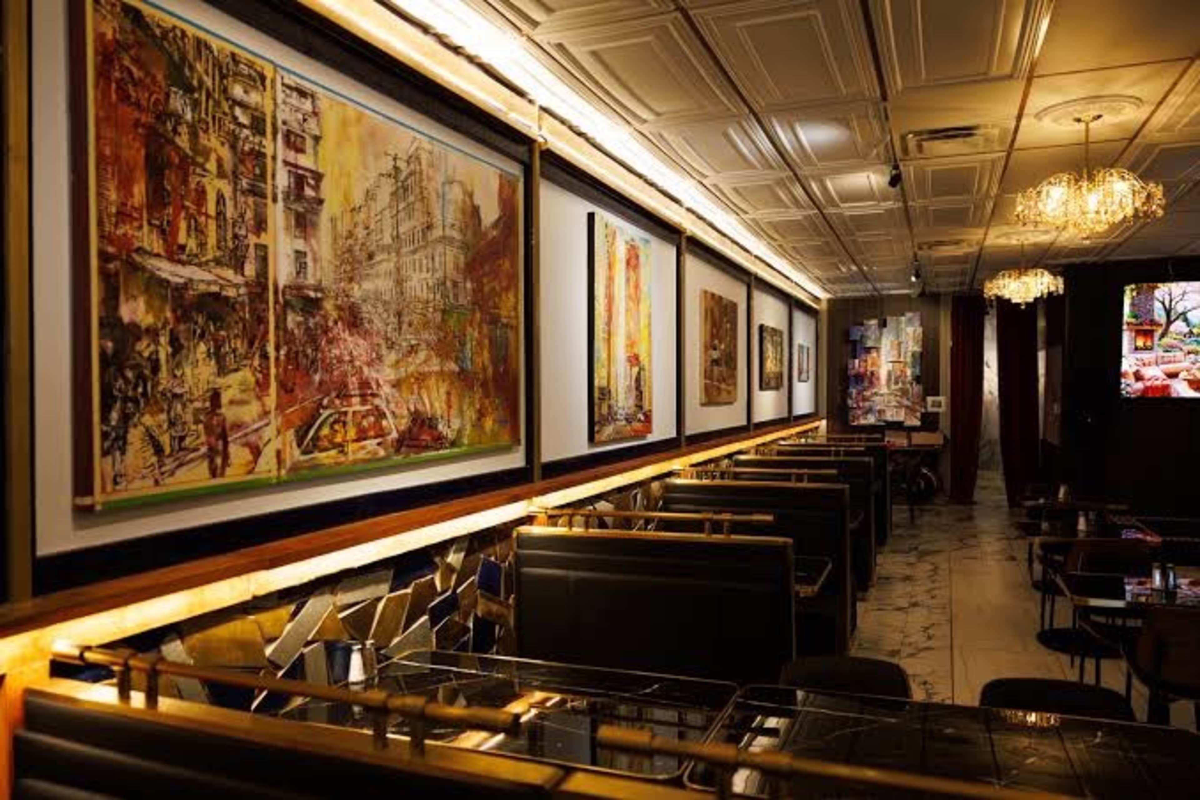 The image shows a stylish restaurant interior featuring modern decor, large paintings on the walls, and cozy seating arrangements.
