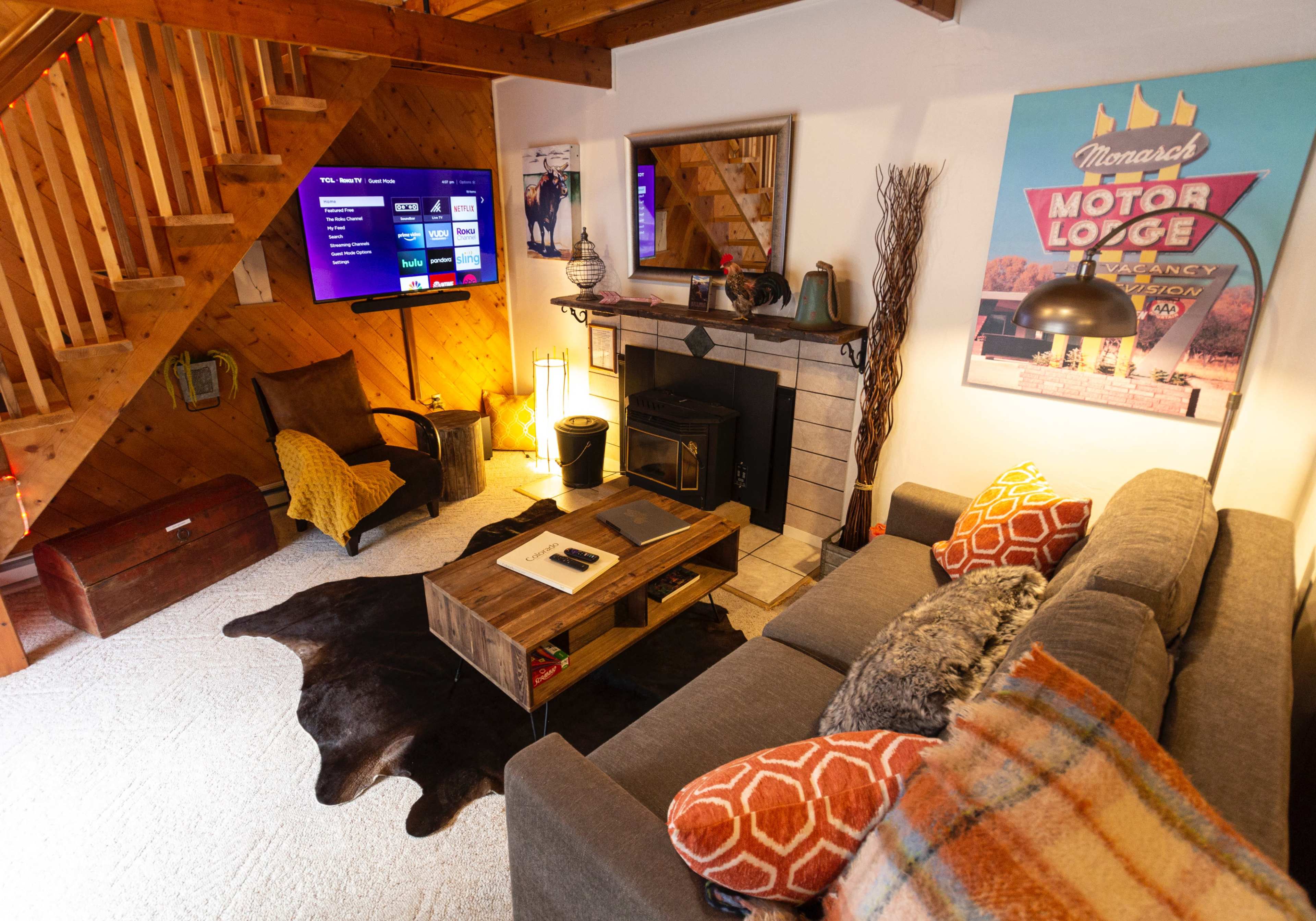 A cozy living room with a gray sectional sofa, a wooden coffee table, and a staircase in the background.