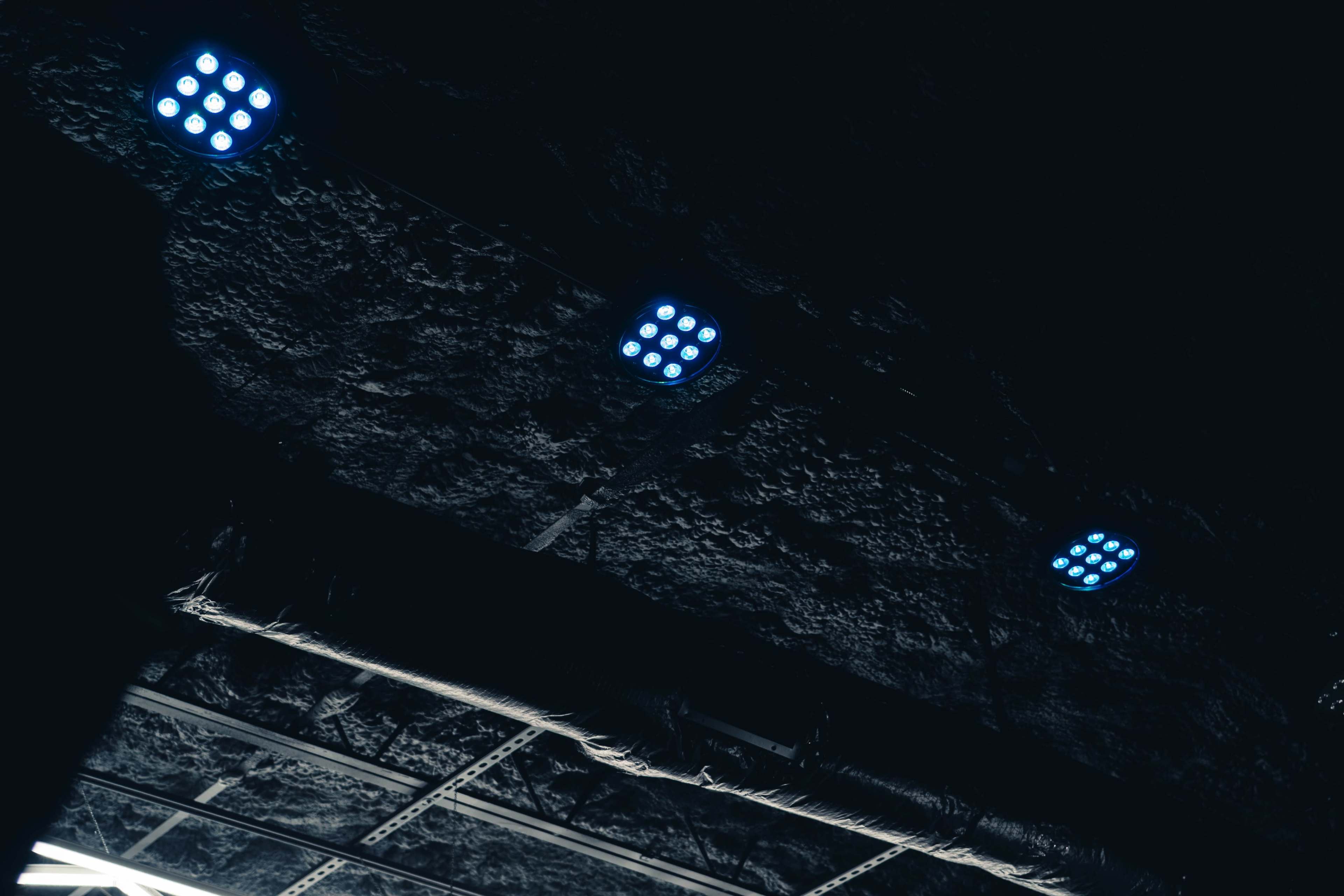 The image shows a dark ceiling with several blue LED lights mounted on it.