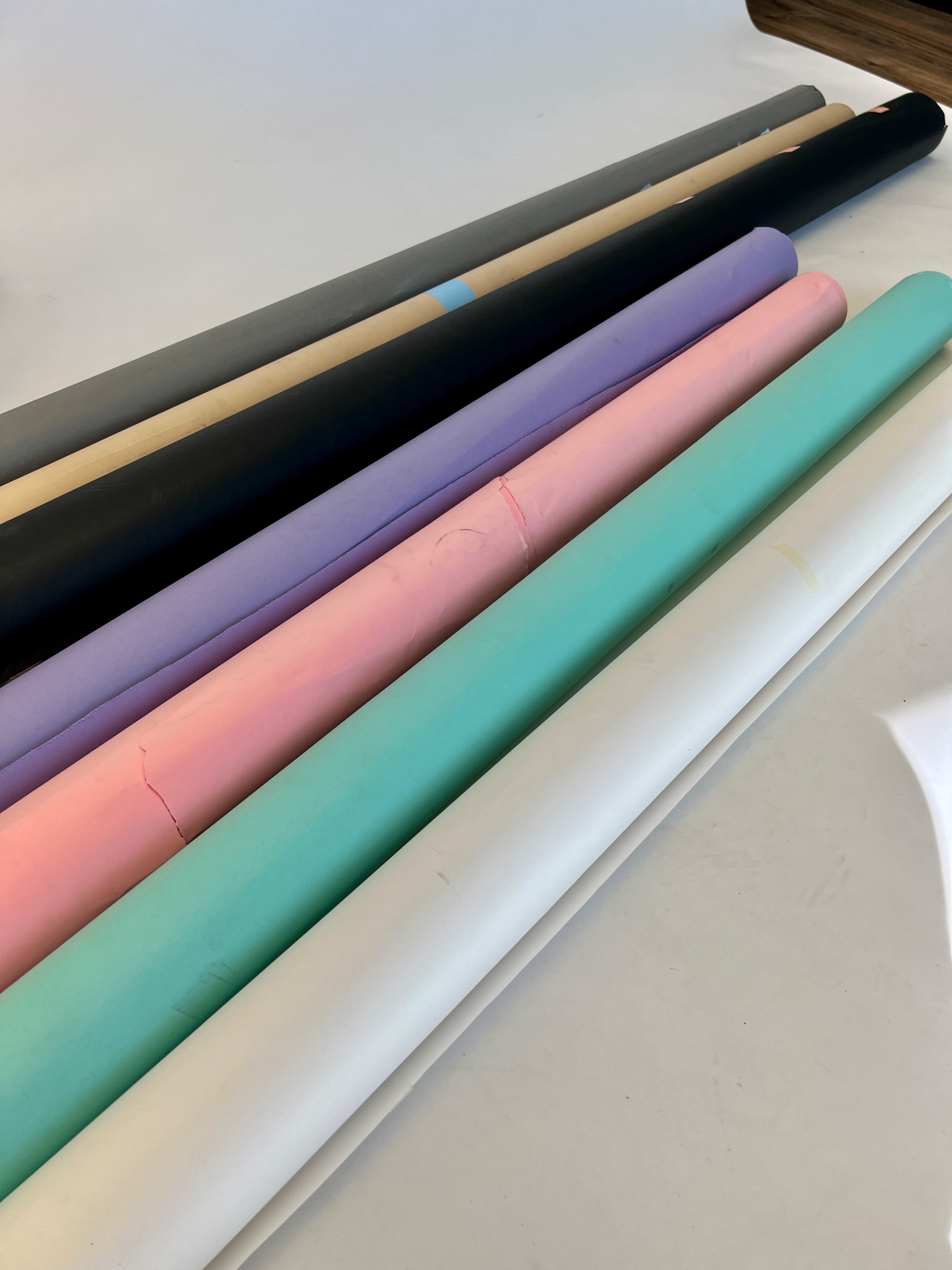 A row of rolled paper in various colors lies on a flat surface.