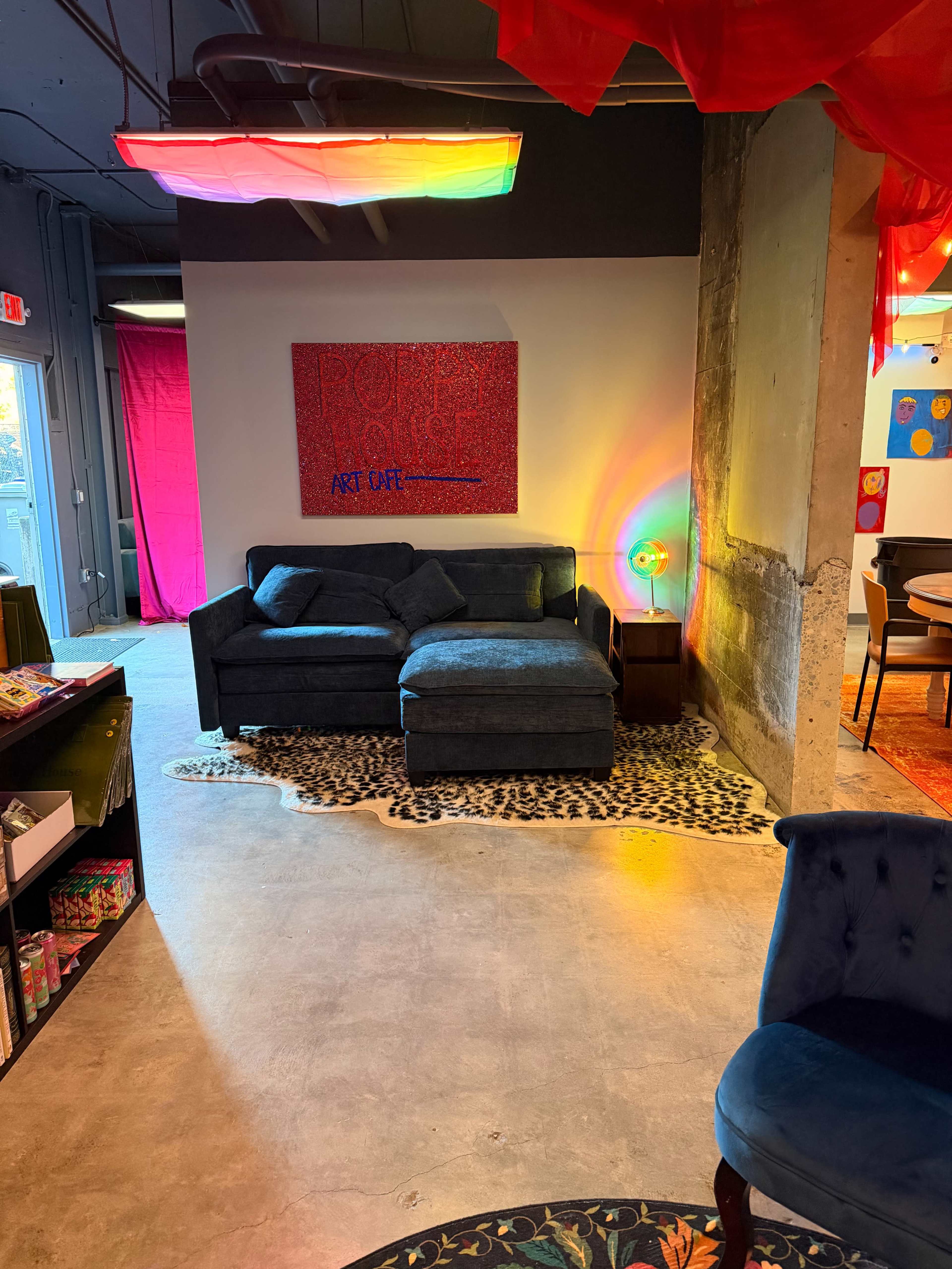 The image shows a colorful lounge area with a blue sofa, an abstract artwork on the wall, and various illuminated decorations.