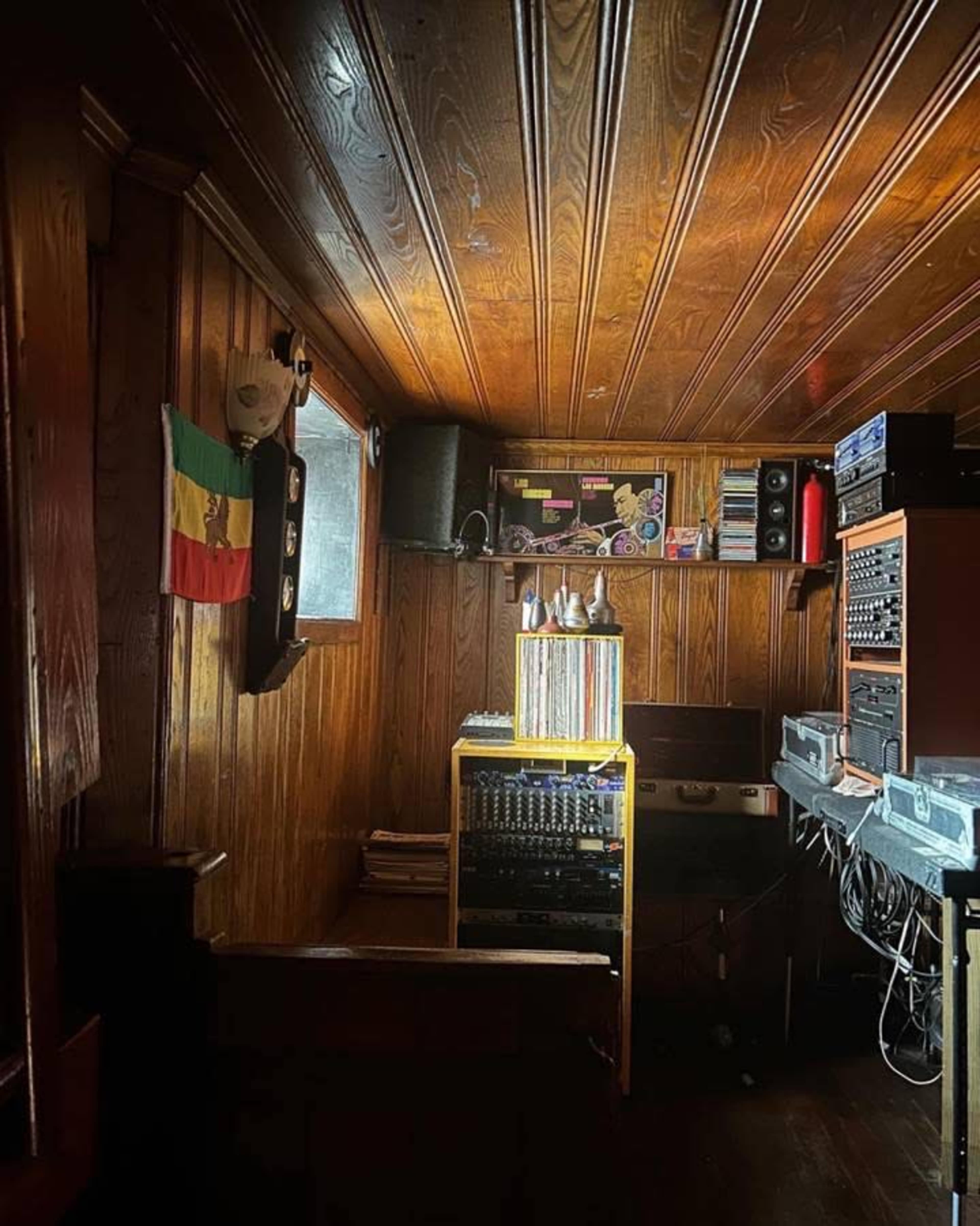 A wooden-paneled room featuring audio equipment, a yellow rack, and a flag displayed on the wall.