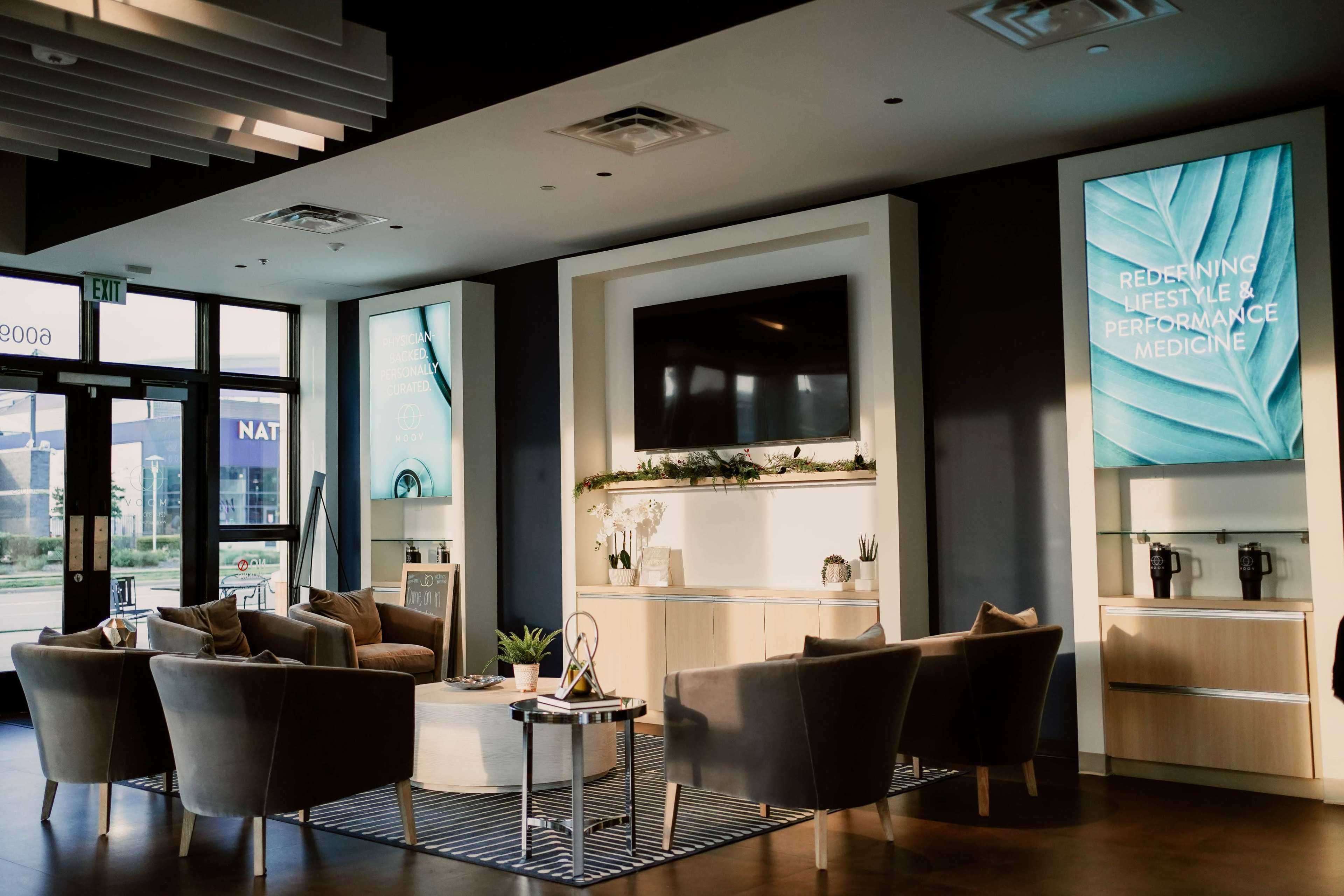 A modern waiting area features stylish seating arrangements, large digital displays, and contemporary decor.