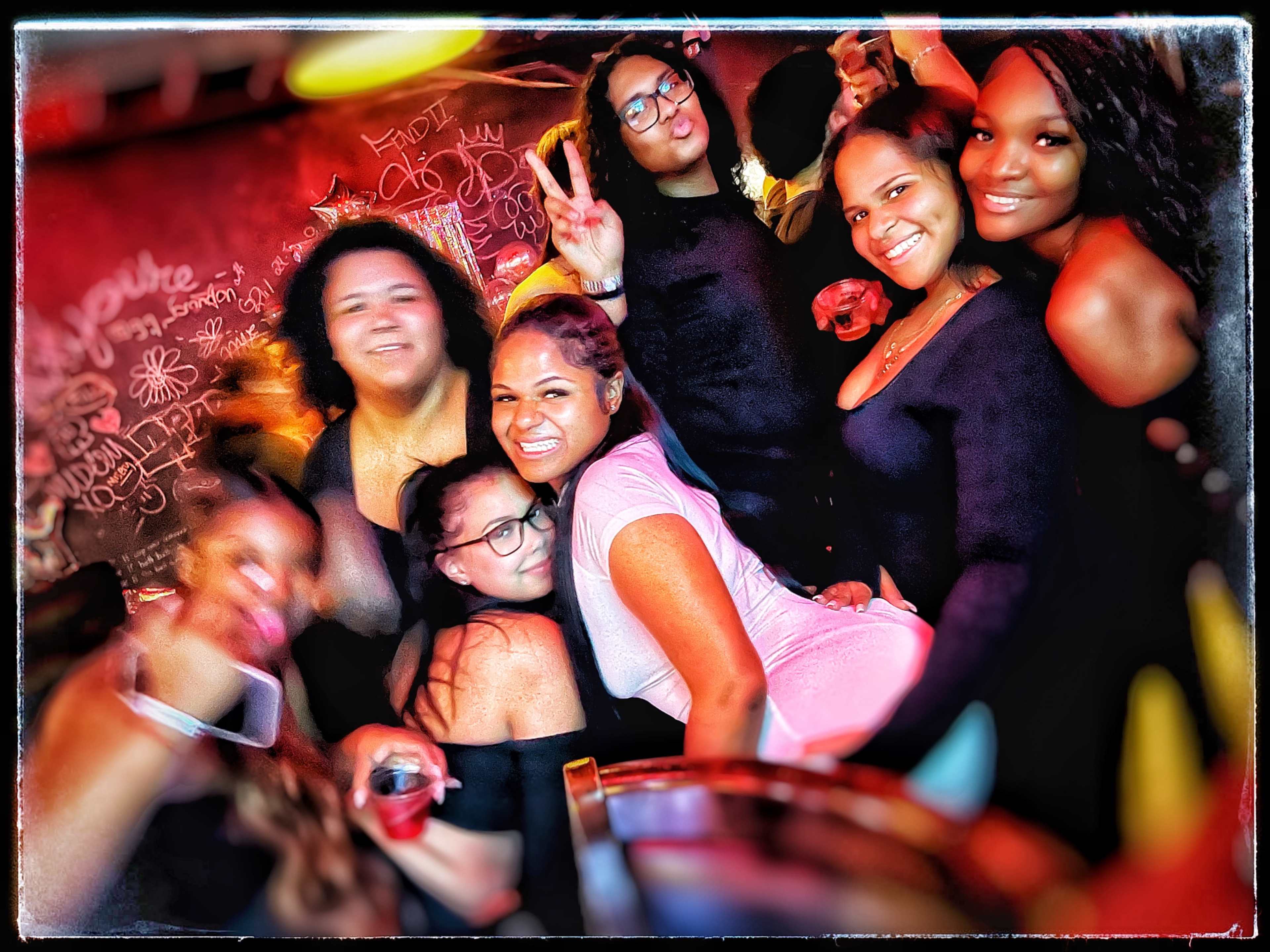 A group of people poses together in a lively bar, smiling and enjoying their time.
