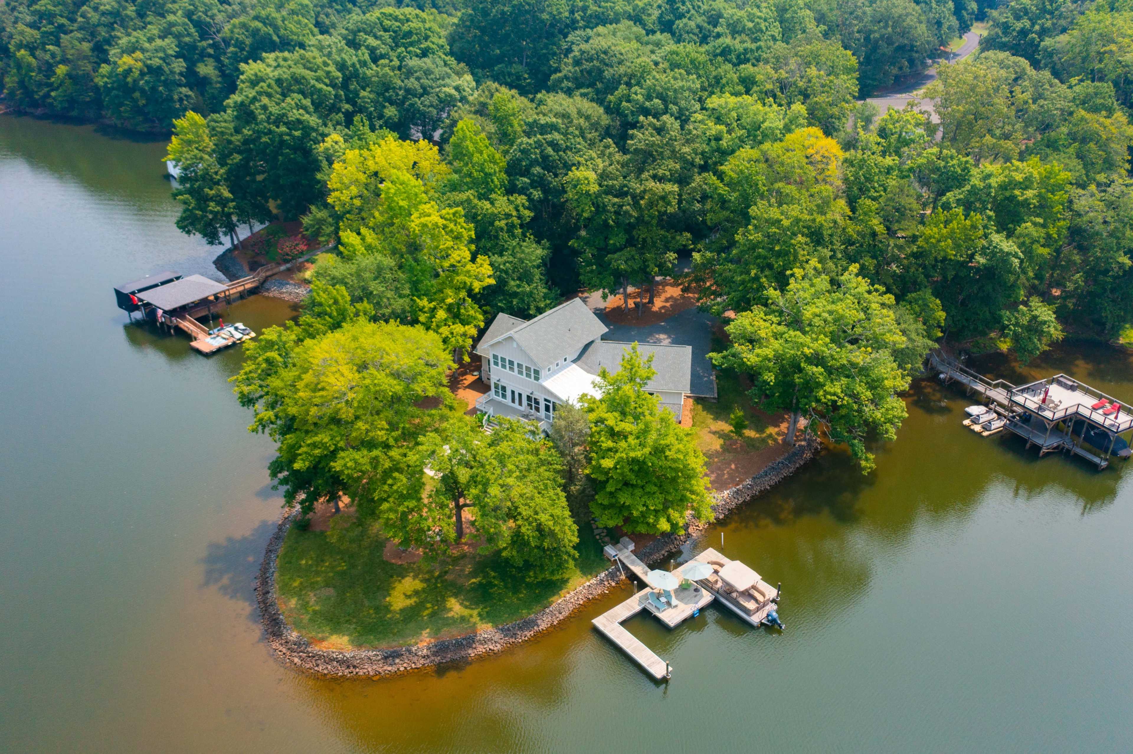 A waterfront property surrounded by trees, with docks on either side of the water.