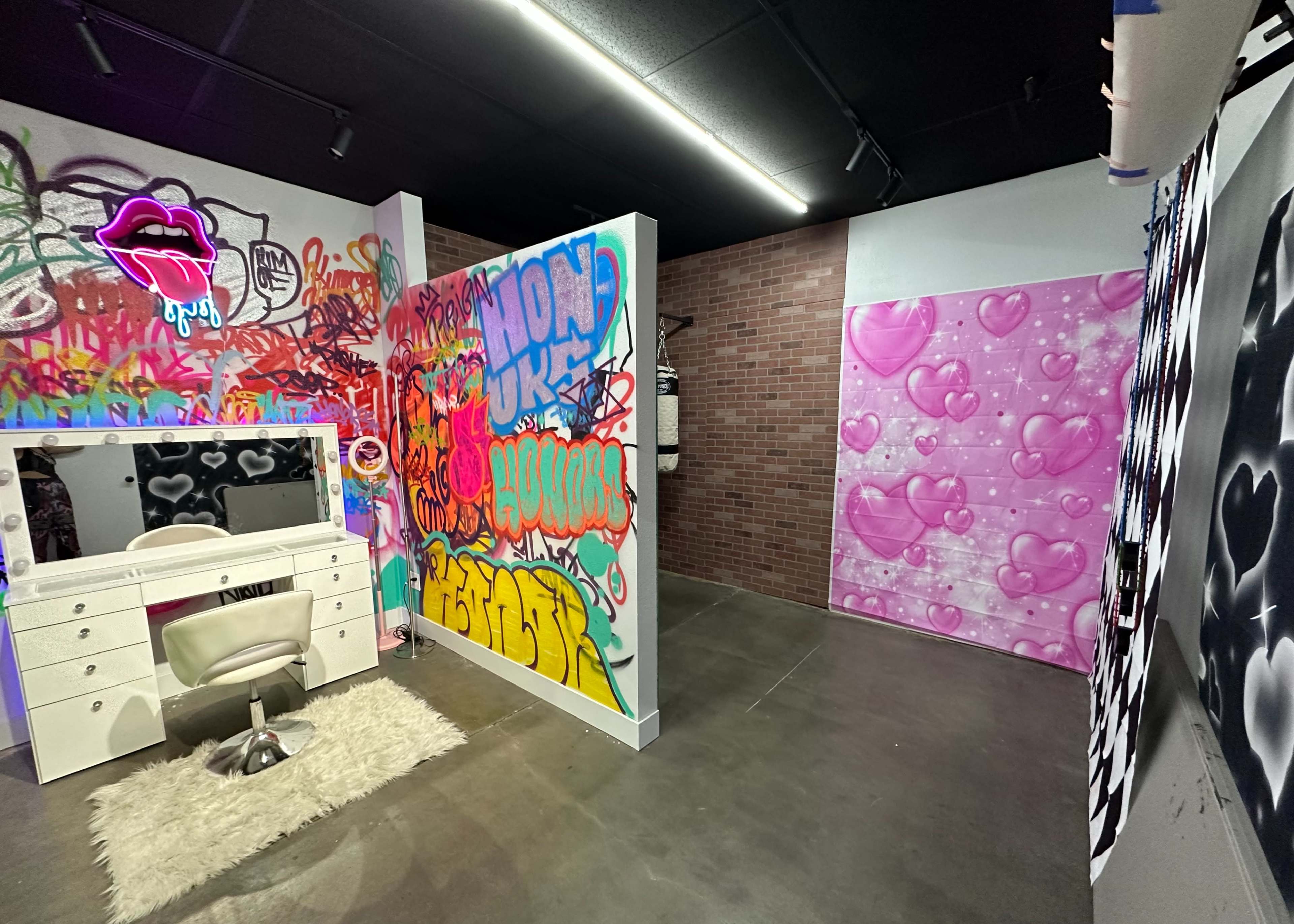 A decorative room featuring a white vanity with a chair, surrounded by colorful graffiti on the walls, including hearts and abstract designs.